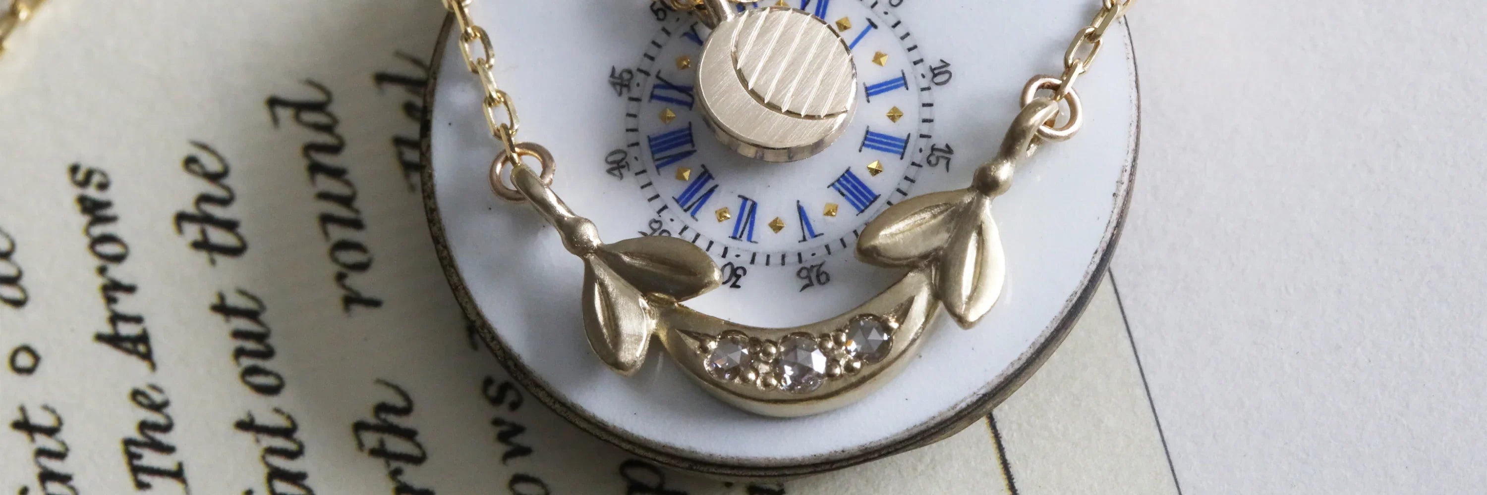 Close-up of gold crescent moon necklace with clear crystals on vintage clock face, soft natural light