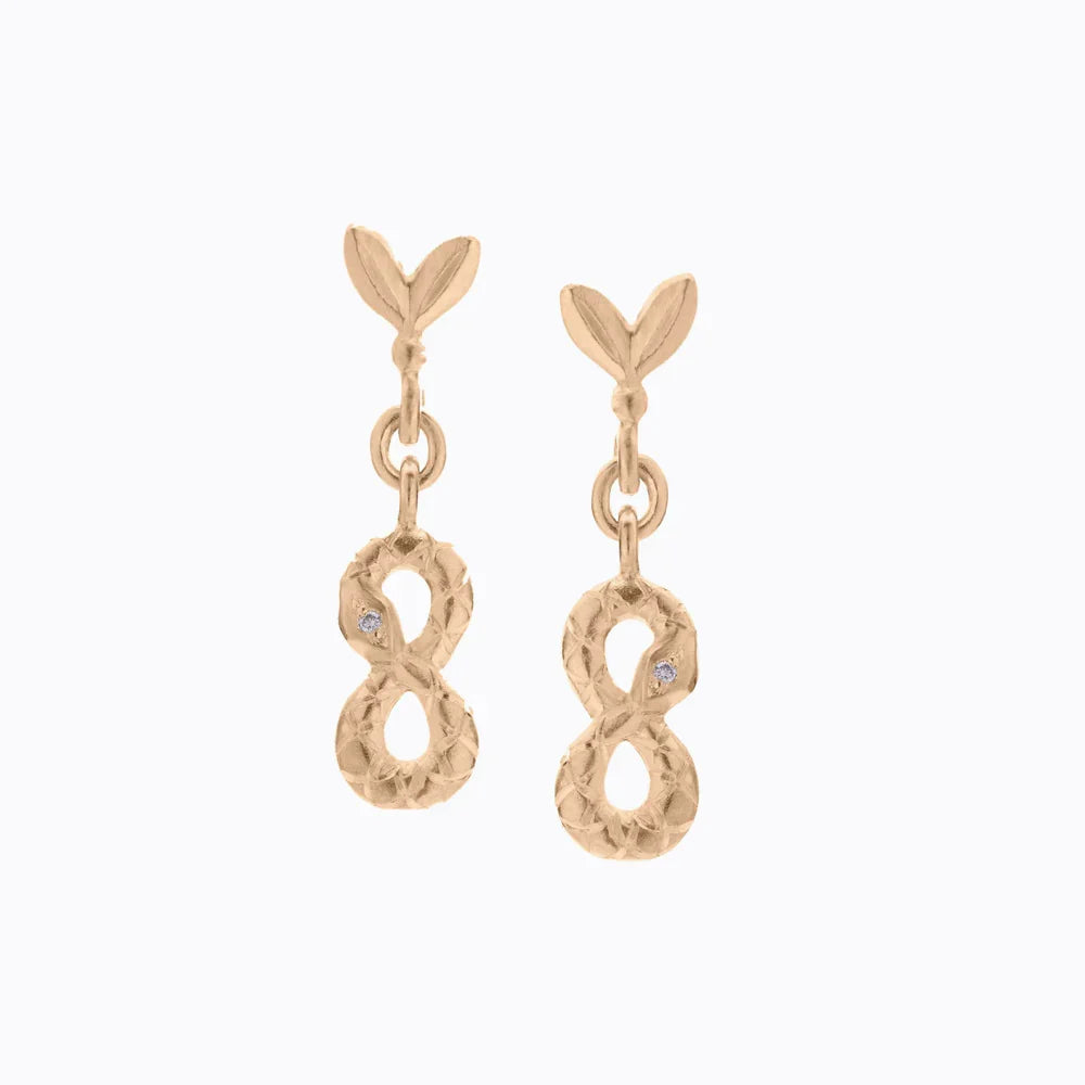 Hand-fabricated gold infinity drop earrings with textured finish and small diamond accents on white background