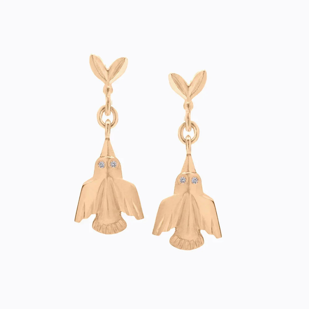 Delicate hand-fabricated gold hummingbird earrings with diamond eyes, soft natural light on neutral background
