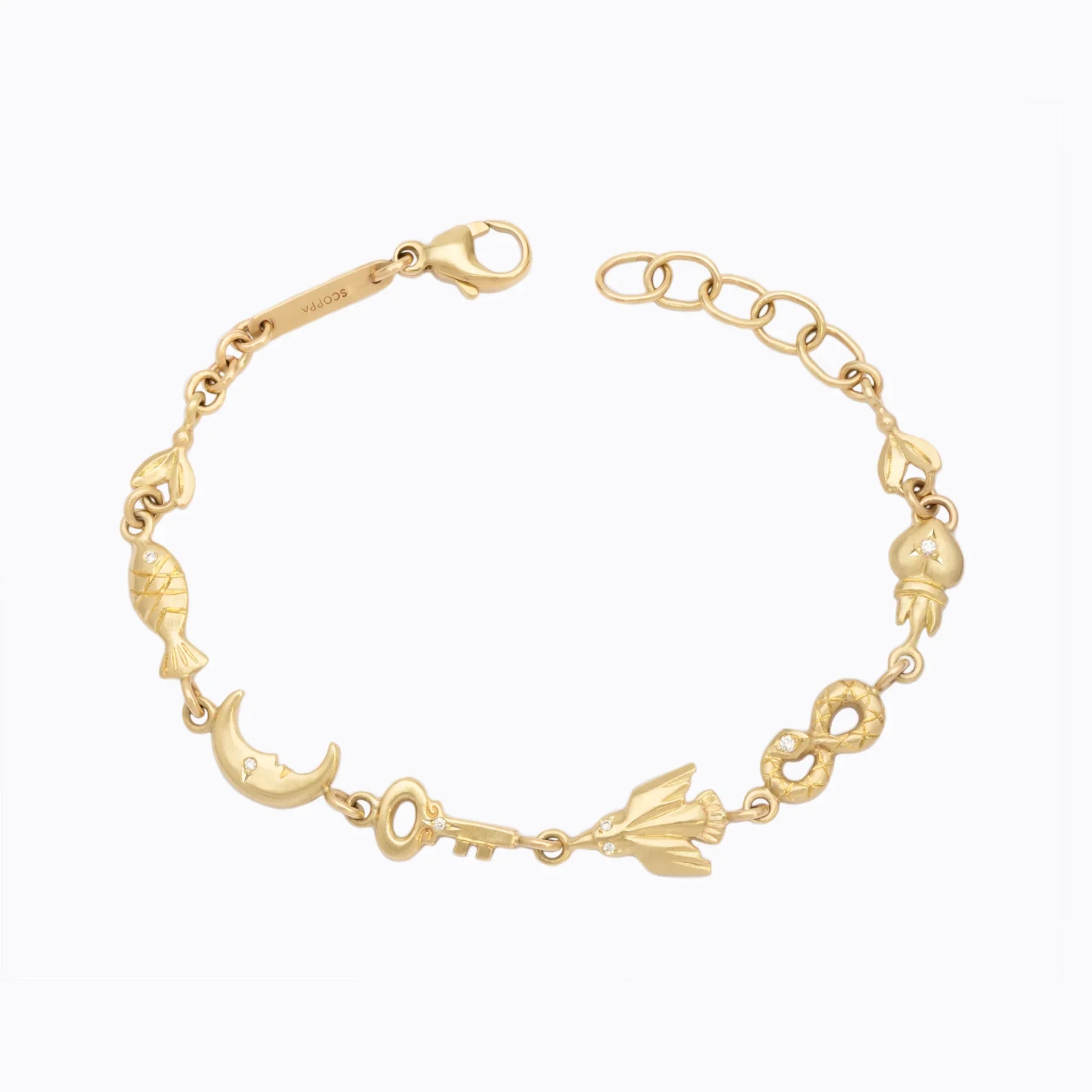 Delicate 18k gold charm bracelet with moon, key, flower, infinity, and fish motifs, soft warm lighting