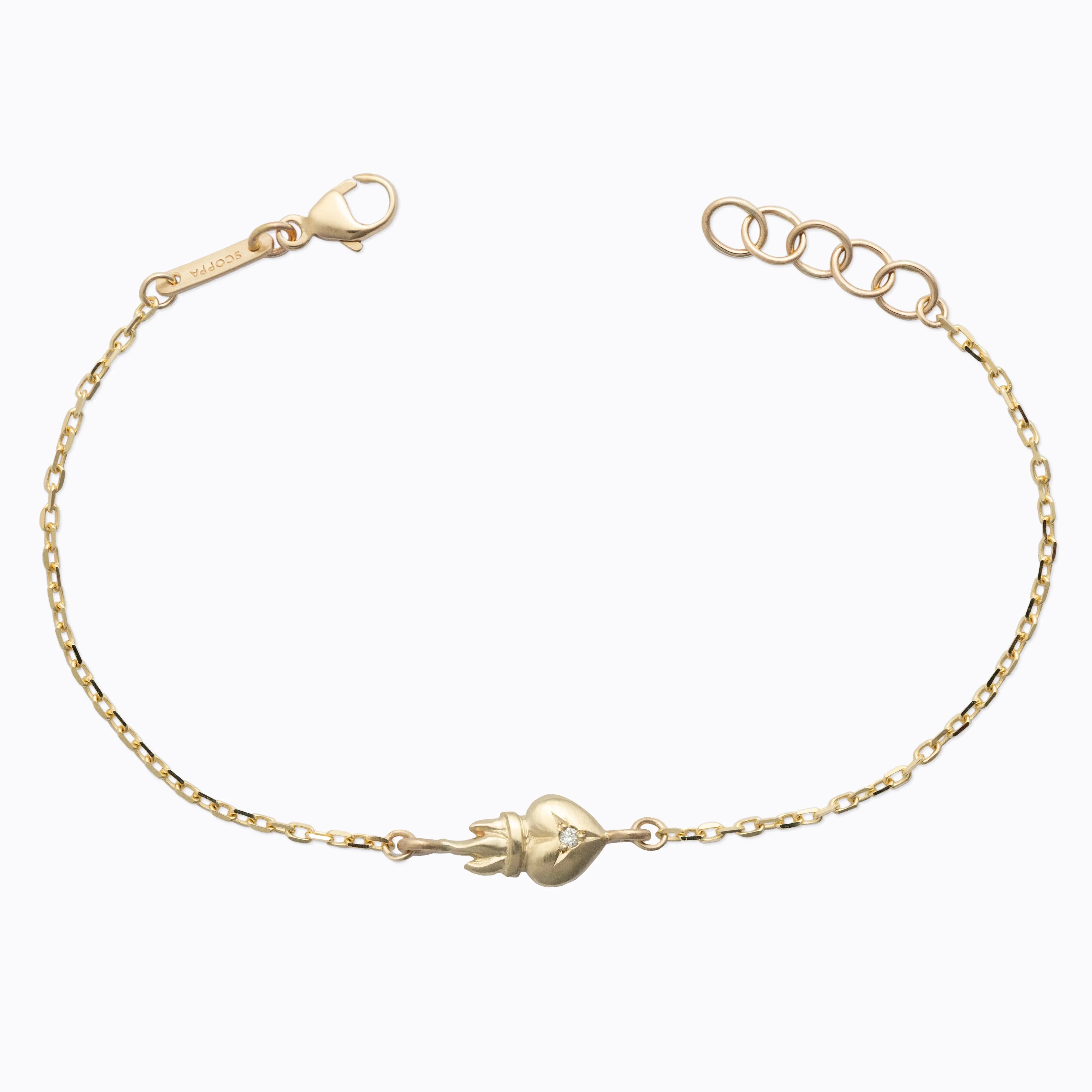 Delicate Fairmined gold bracelet with flame and heart motif, warm natural light on white background