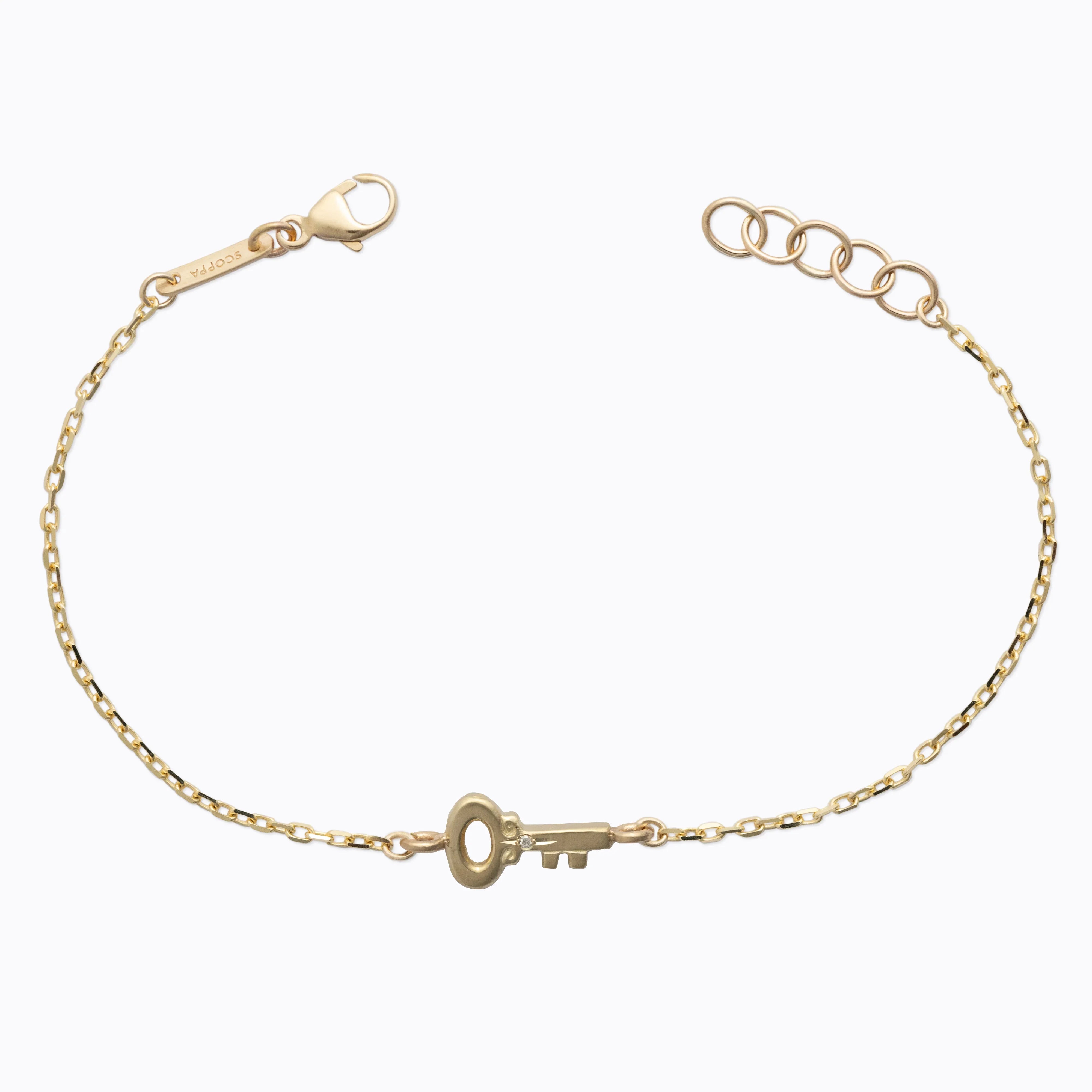 Delicate gold key bracelet with fine chain and lobster clasp on soft white background