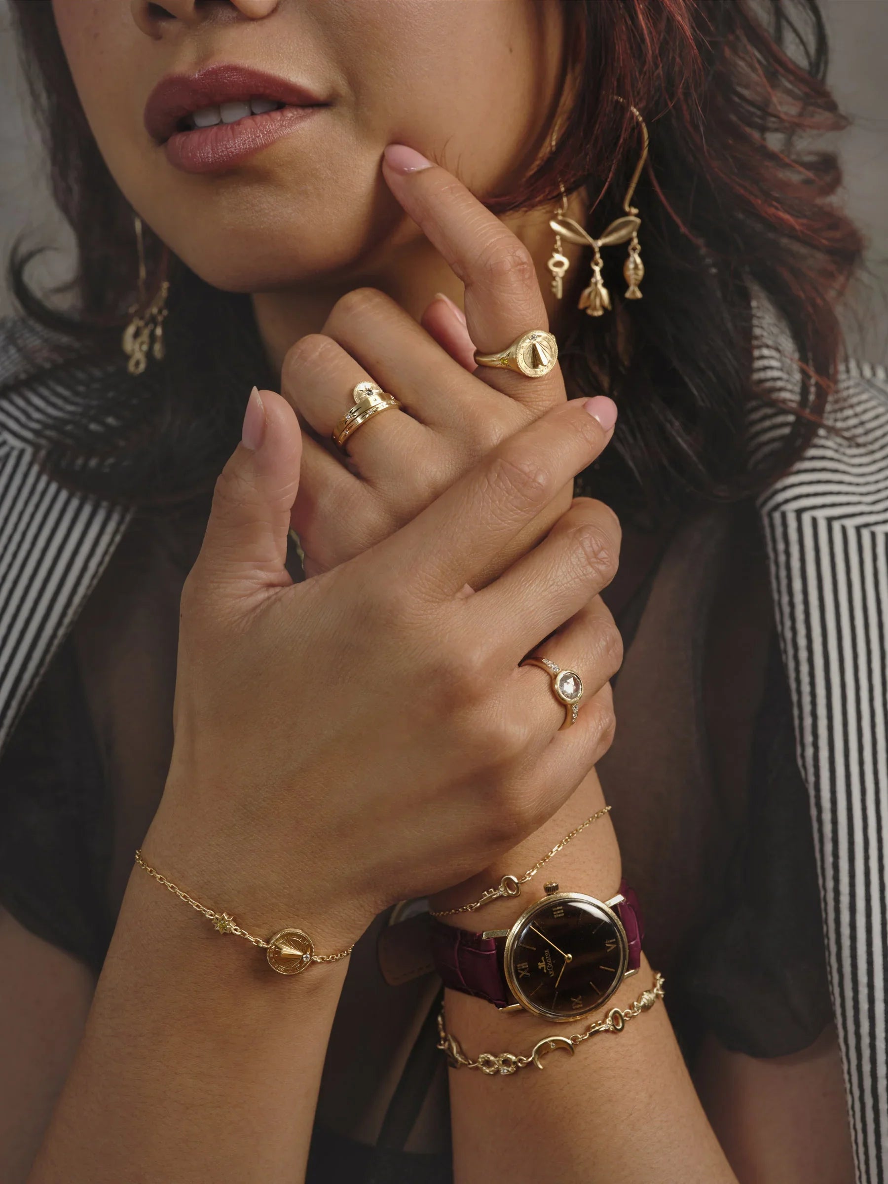 Close-up of woman's hand with handcrafted gold sundial rings and bracelet, gold watch, warm natural light