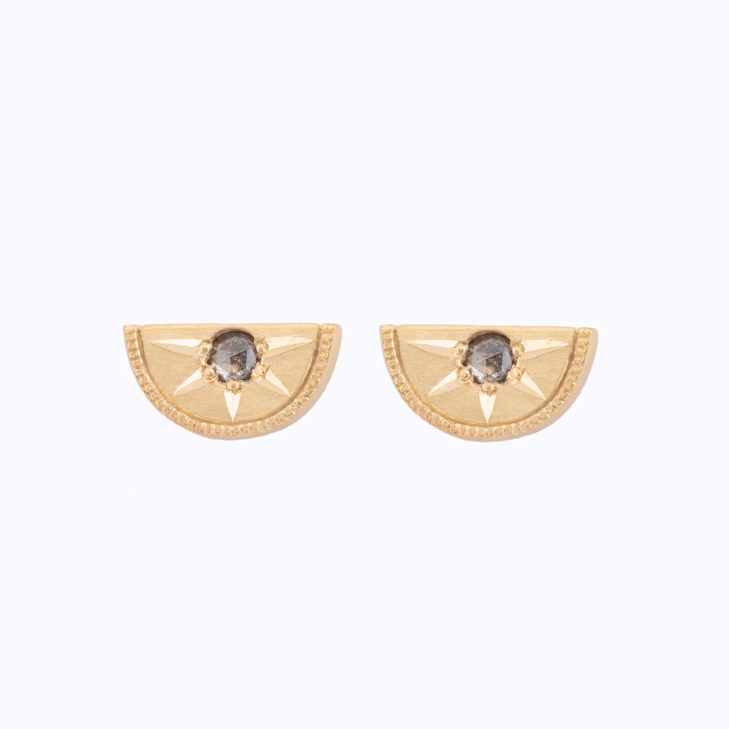 Pair of handcrafted gold half-circle stud earrings with central dark gemstone and engraved starburst detail on white background