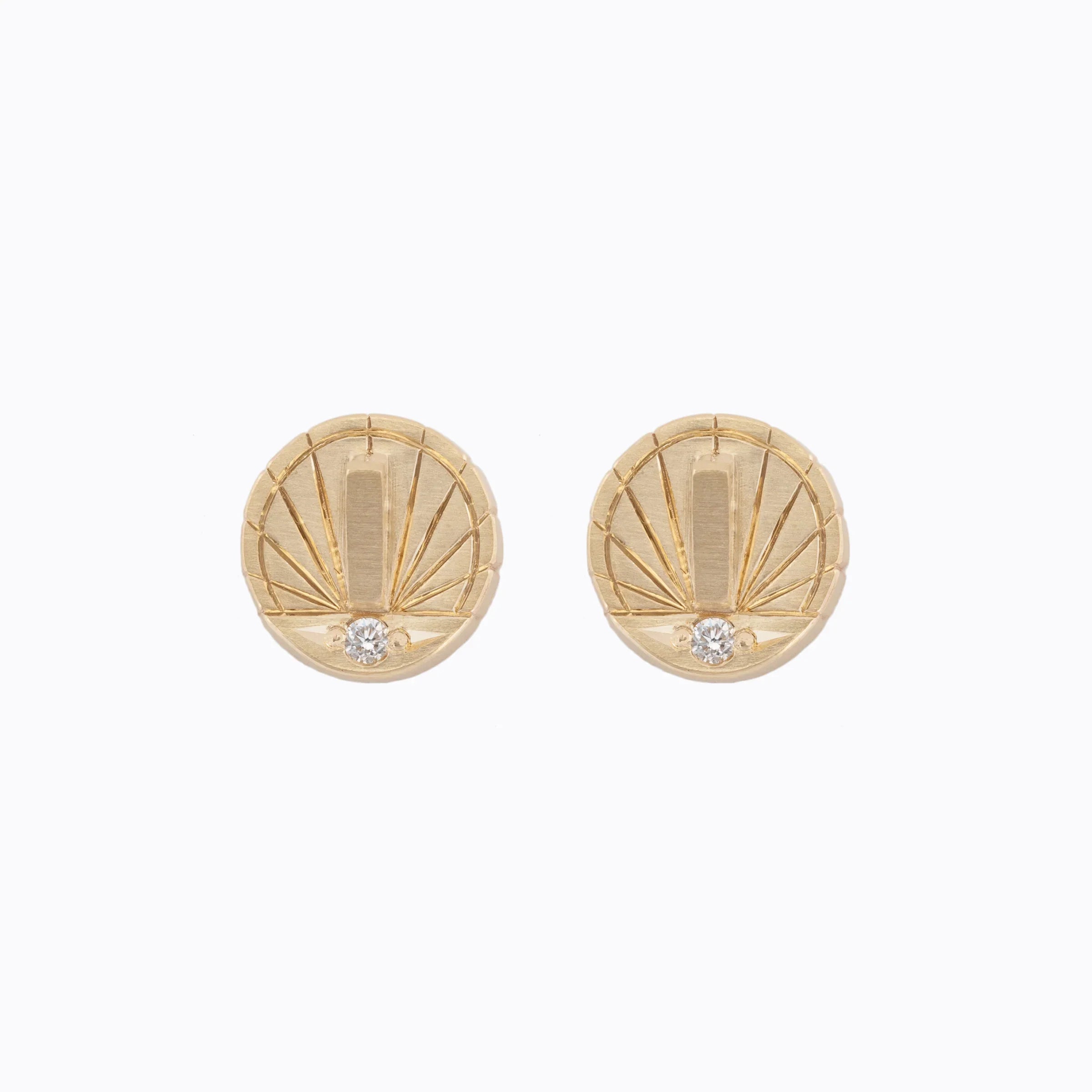 Pair of hand-fabricated Fairmined gold sundial stud earrings with engraved rays and small gemstone, on white background