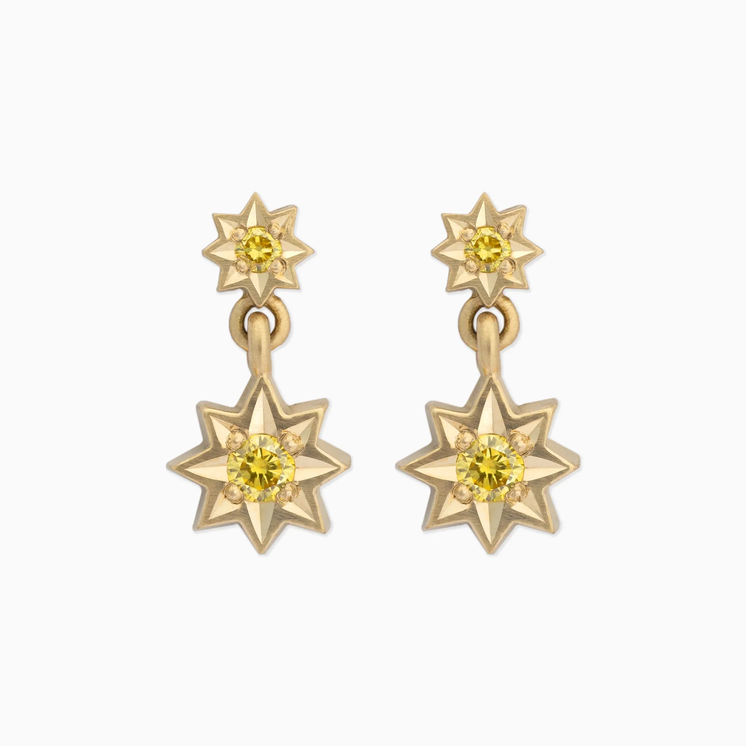 Elegant pair of gold star-shaped drop earrings with yellow gemstone centers on white background