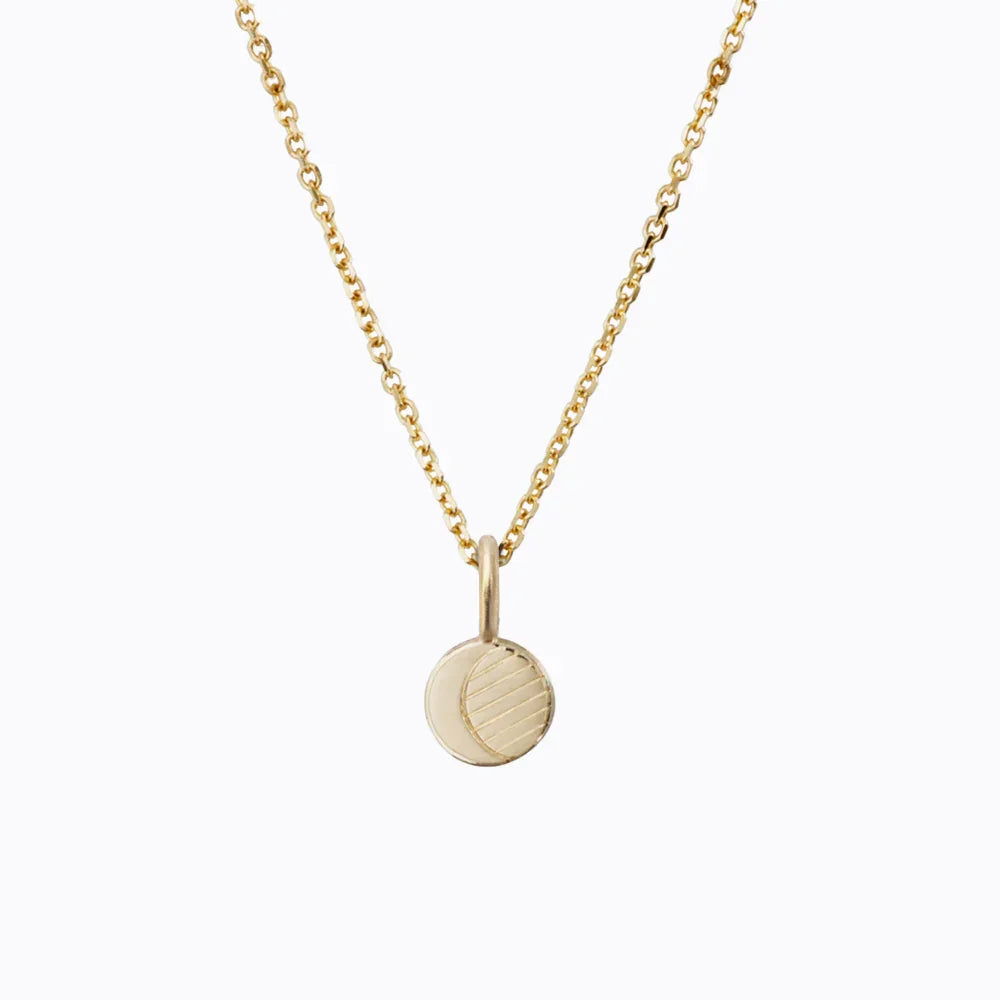 Delicate gold moon phase pendant necklace with hand-engraved half moon design on white background