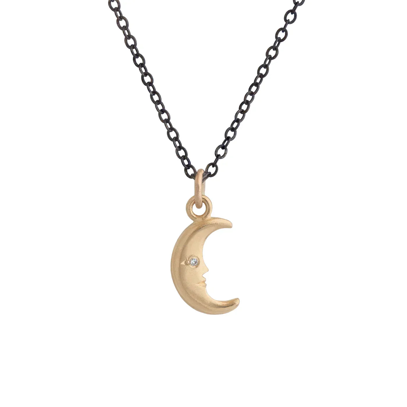 Gold crescent moon pendant with diamond eye on dark chain against white background