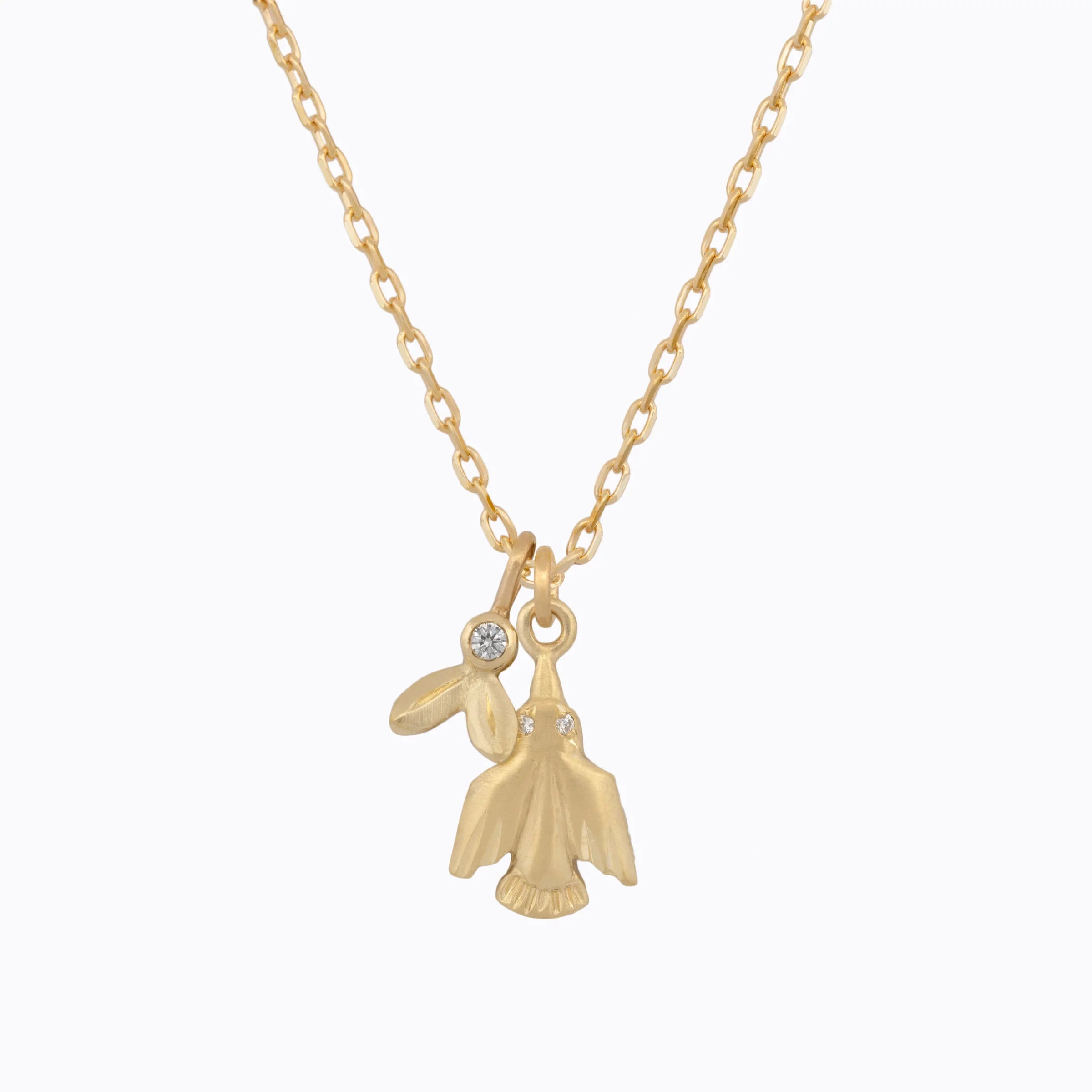 Delicate gold hummingbird pendant necklace with small diamond accents, minimalist white background