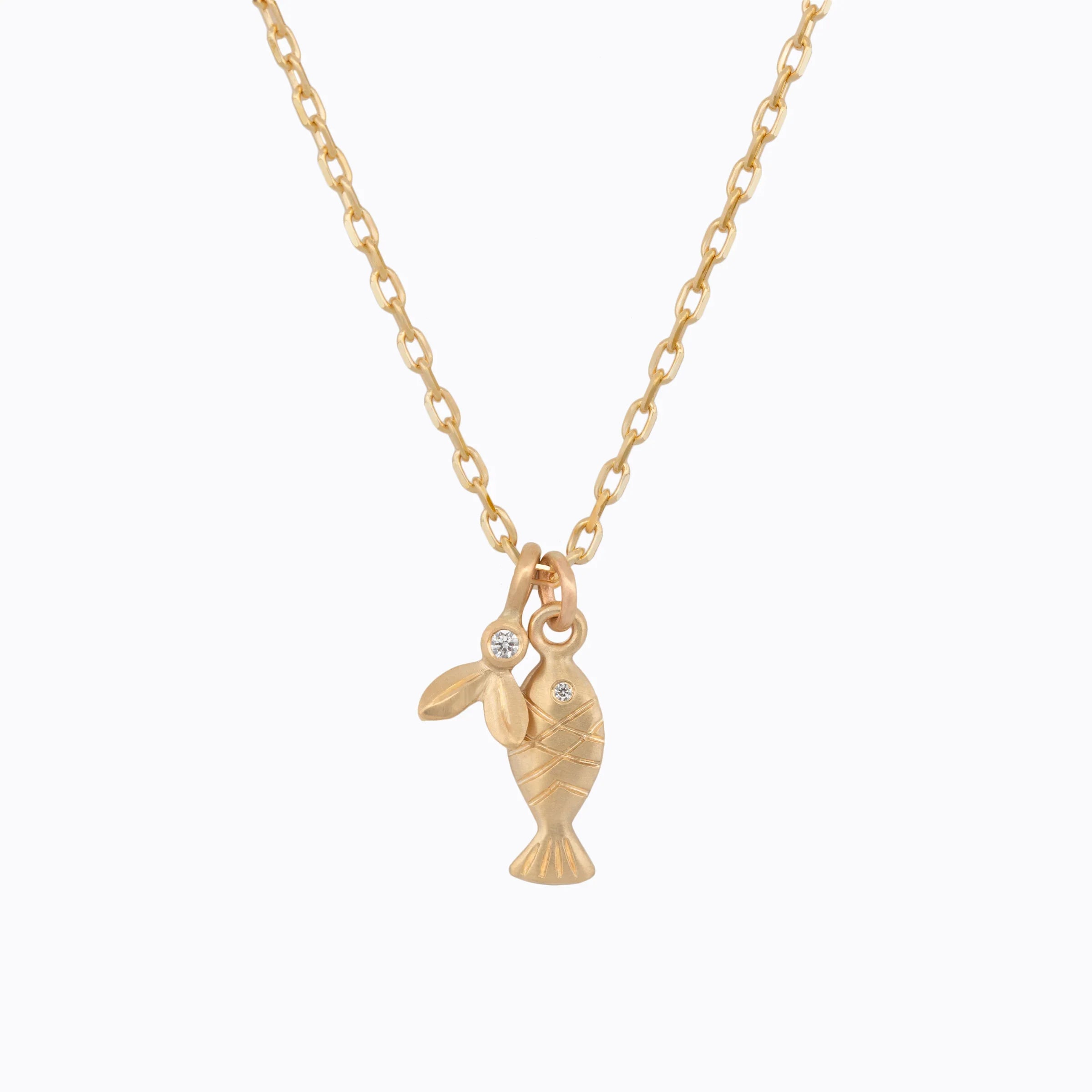 Delicate 18k gold fish and leaf charms on fine chain with small embedded diamonds, minimalist white background