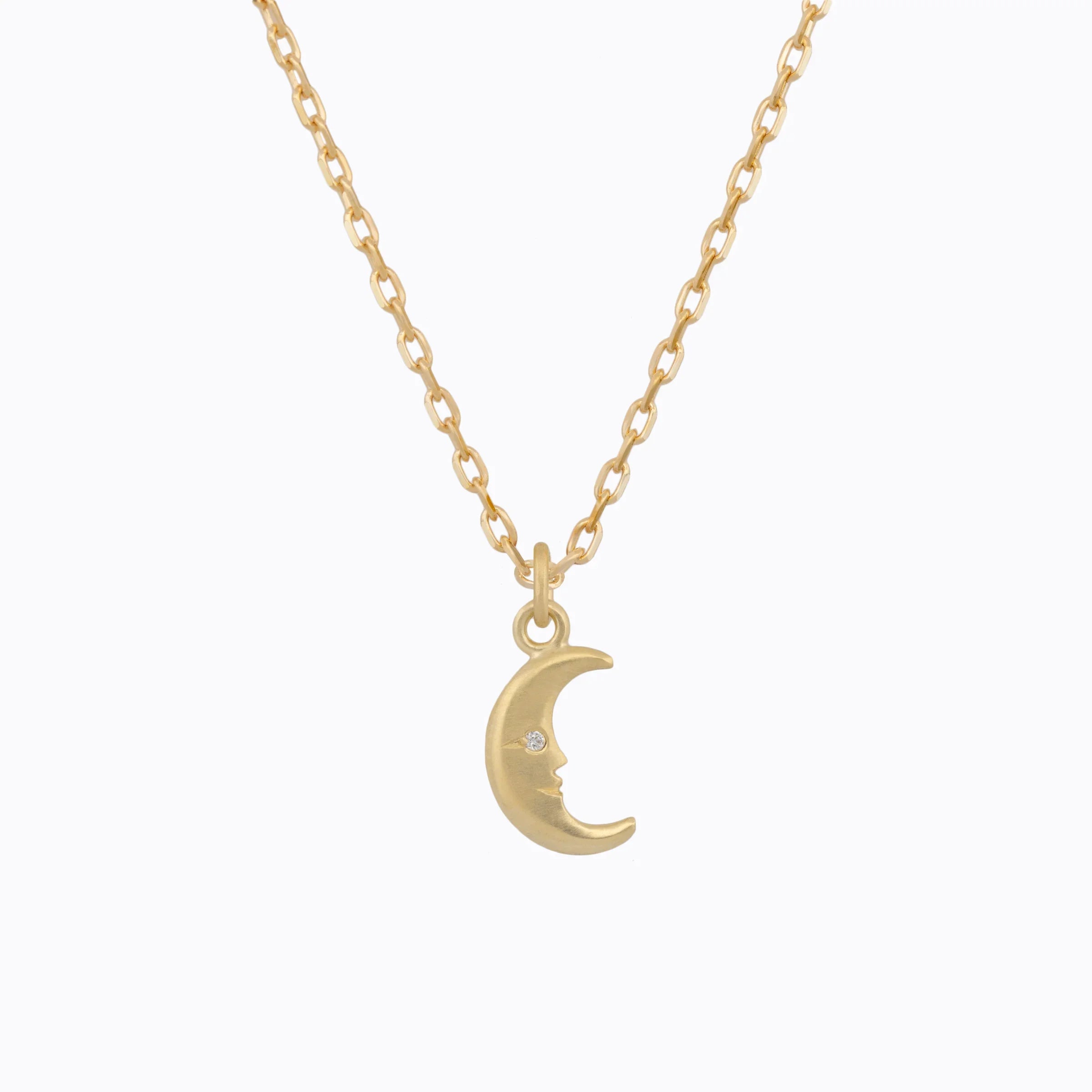 Elegant gold moon phase pendant with engraved crescent moon face and small diamond eye on delicate chain