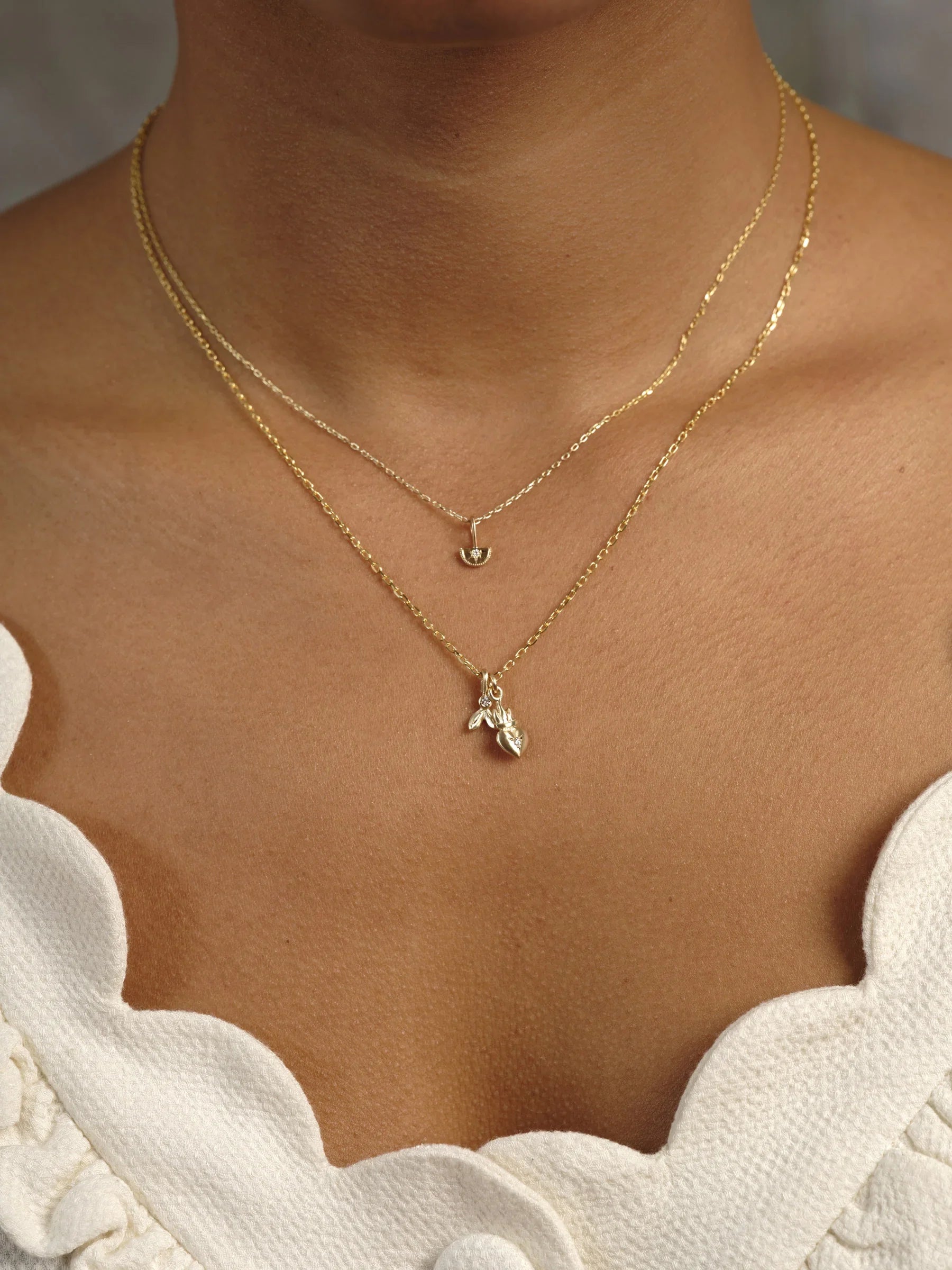 Warm golden hour close-up of layered delicate 14k gold necklaces on natural skin, minimalist neckline