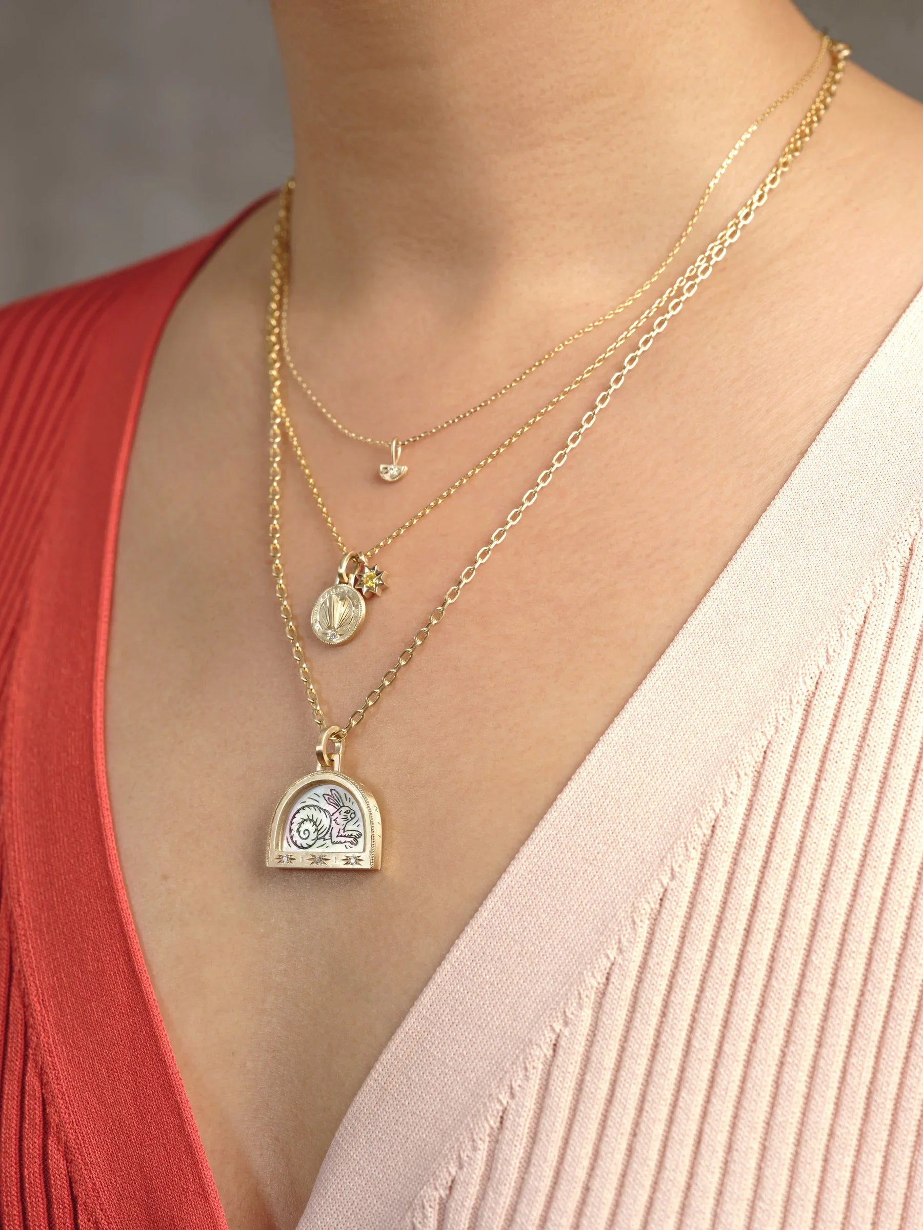 Three-layered gold necklaces with hand-painted rabbit pendant, sunburst charm and dainty moon pendant on woman's neck