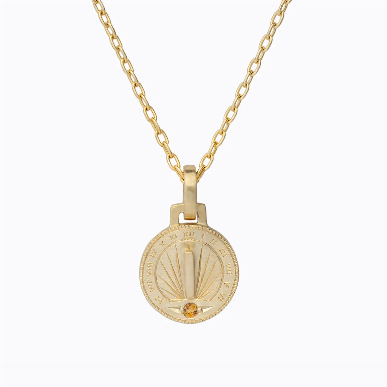 Handcrafted gold sundial pendant necklace with Roman numerals and low amber gemstone on white background