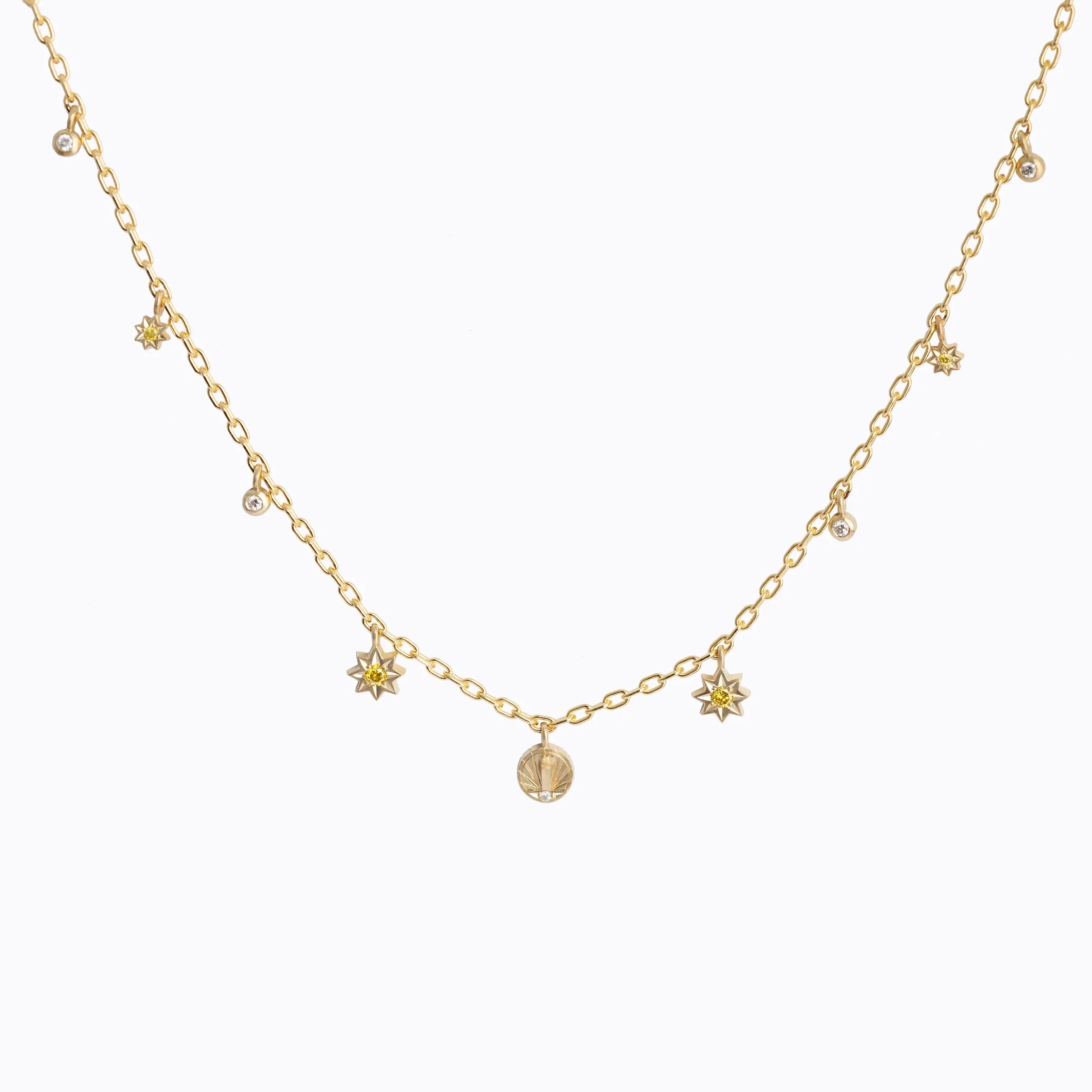 Delicate handcrafted gold chain necklace with sunburst and diamond charms on white background