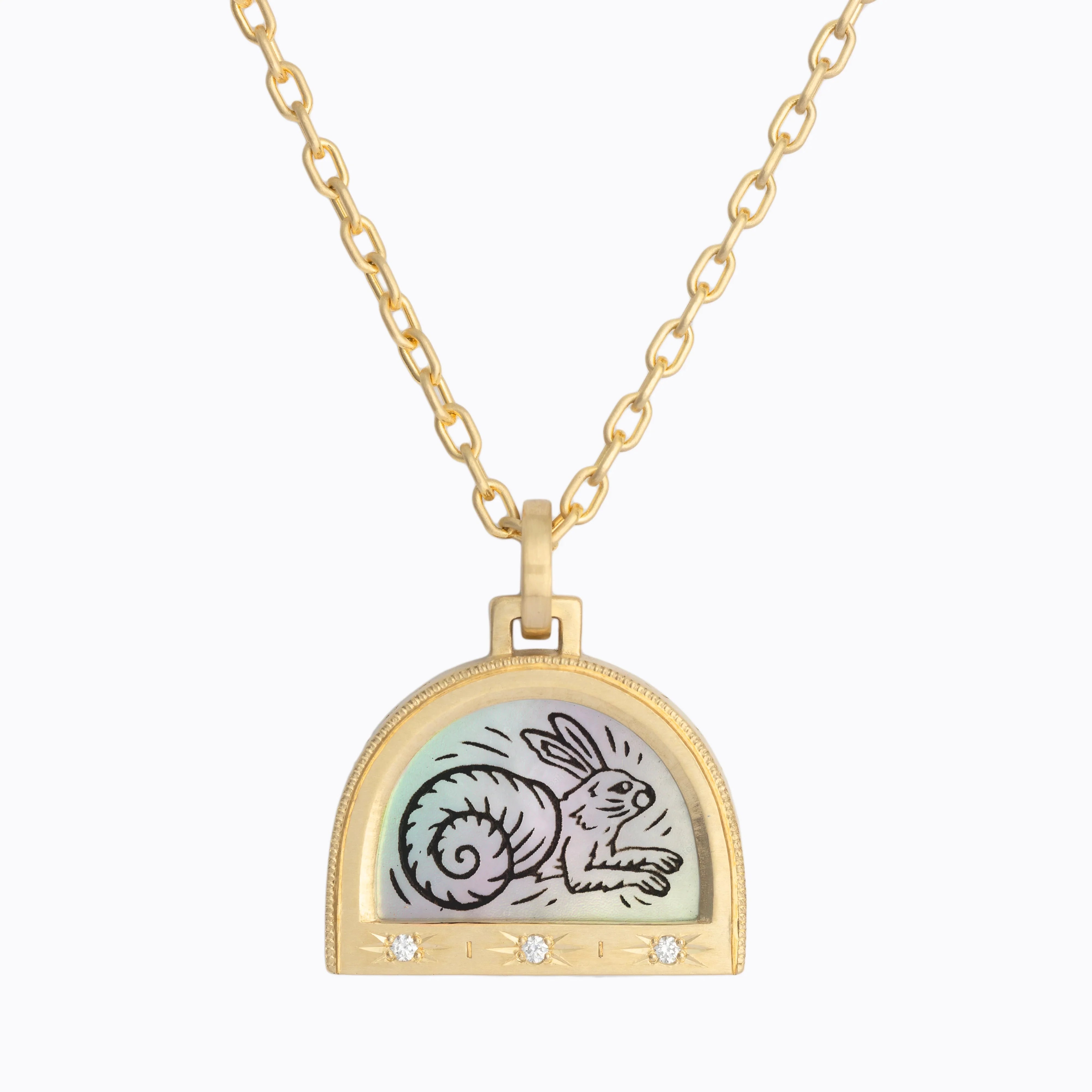 Gold pendant necklace with rabbit and spiral shell drawing on iridescent background, three diamonds on bottom
