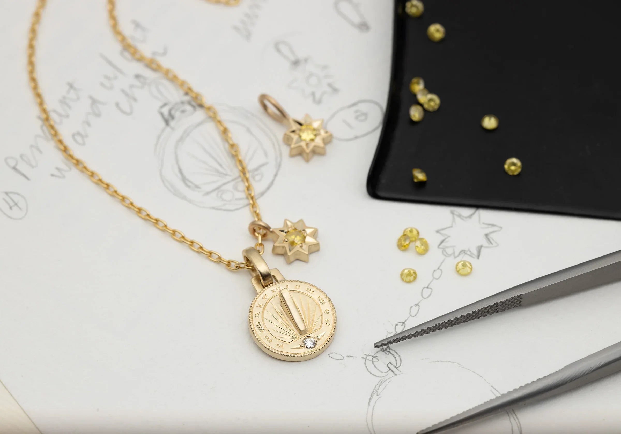 Fairmined gold sundial pendant and star charm with yellow sapphires on jewelry design sketch
