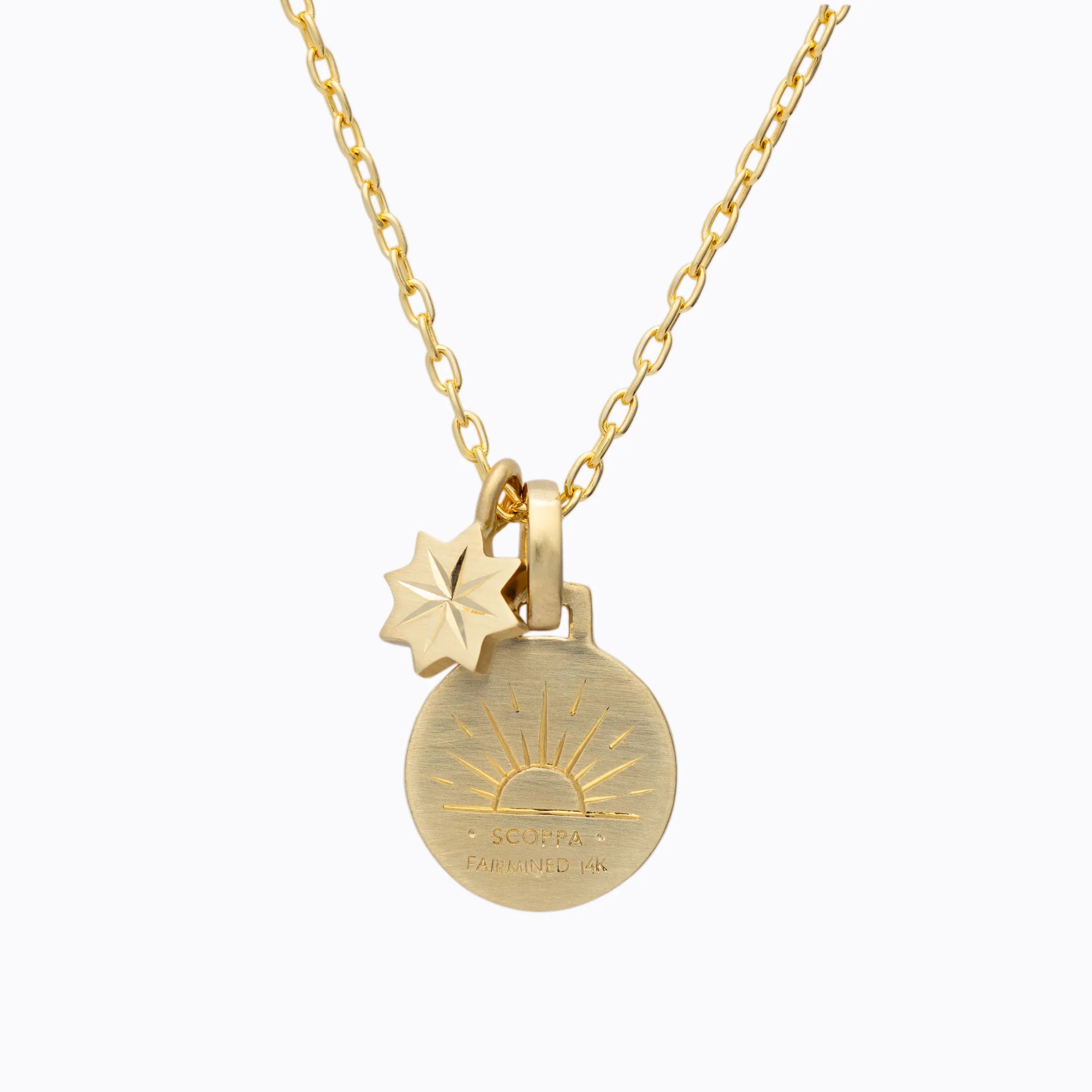 Close-up of 14k Fairmined gold pendant necklace with sun motif and star charm on white background