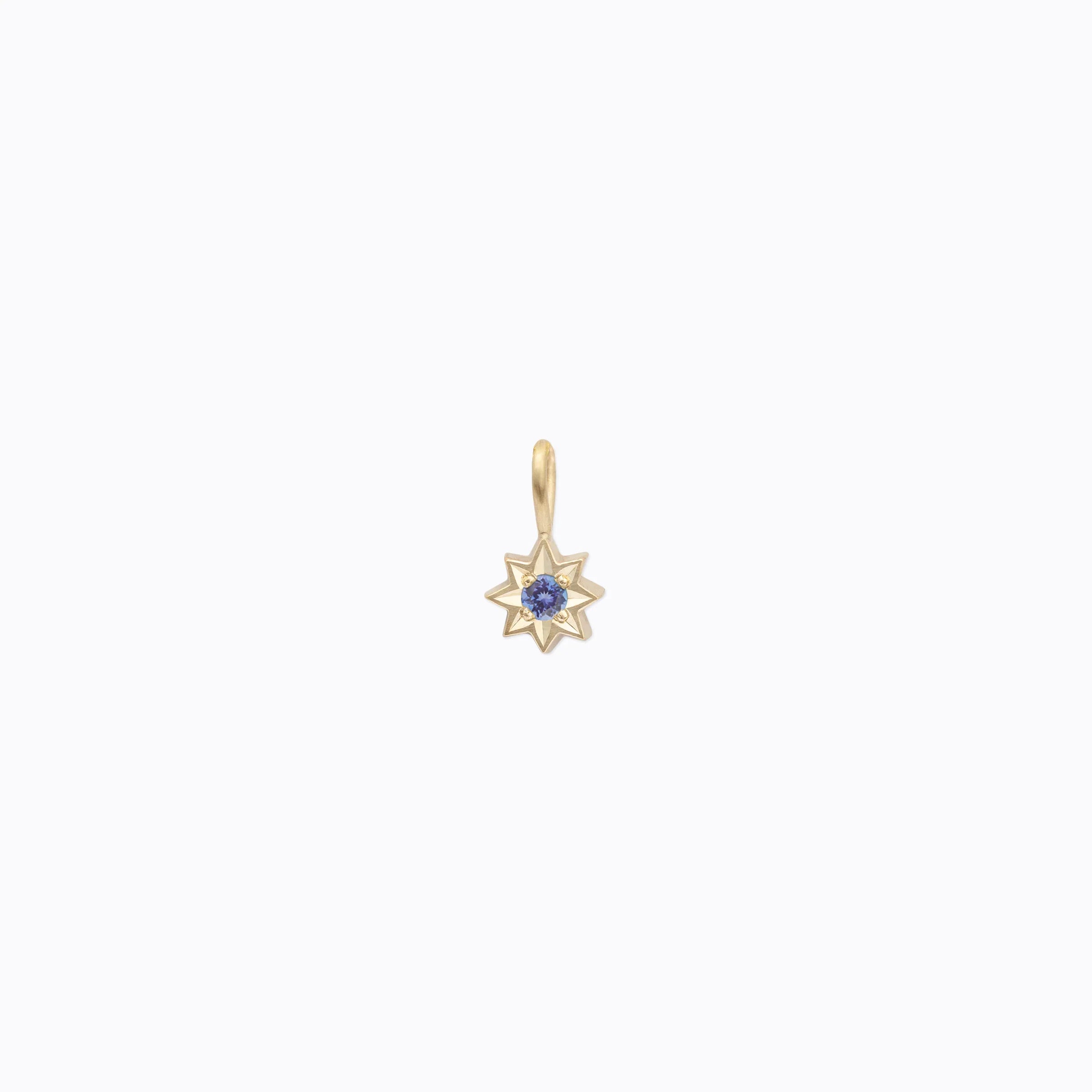 Handcrafted 18k gold star-shaped pendant with deep blue gemstone center on soft white background