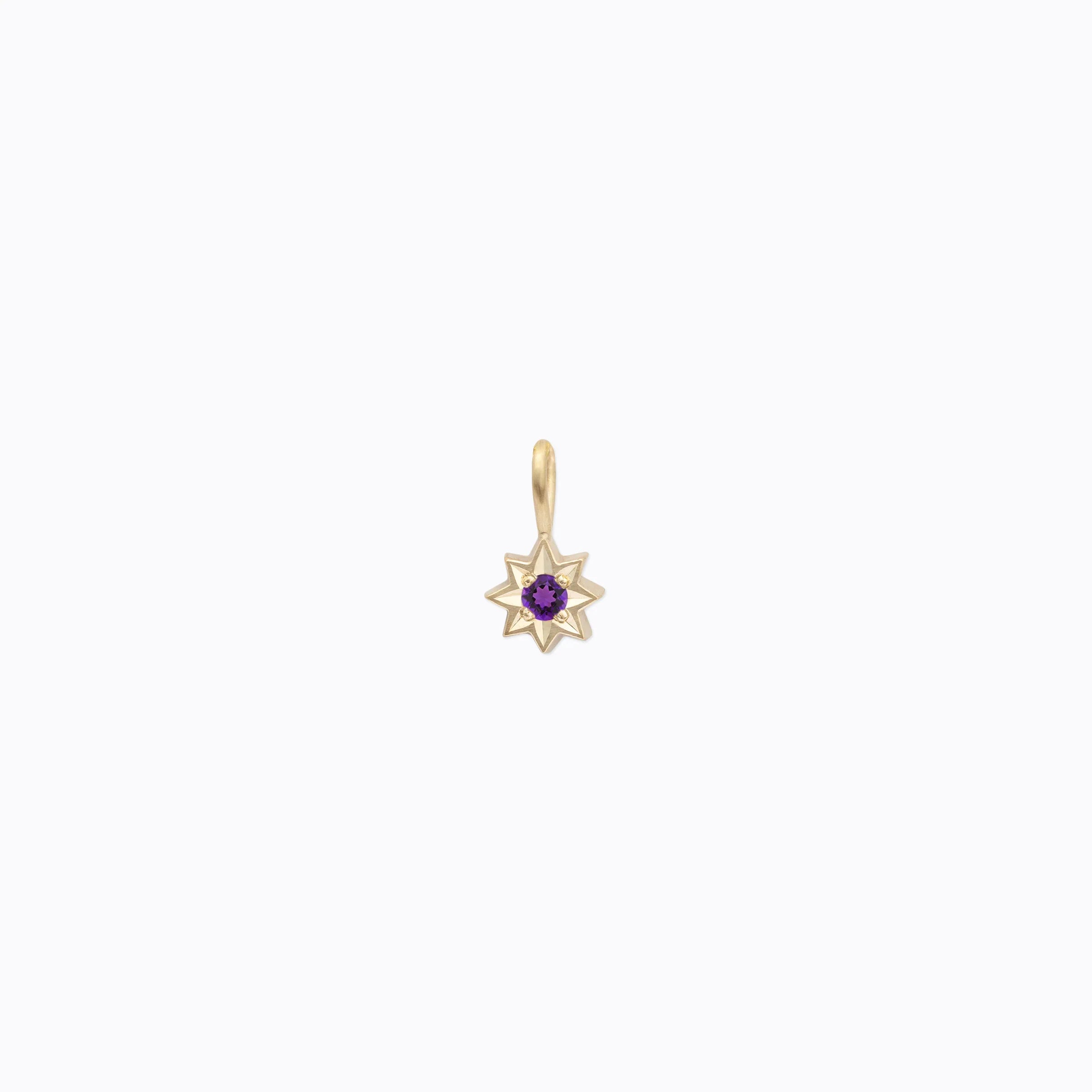 Delicate gold star-shaped pendant with central purple gemstone, photographed on soft white background