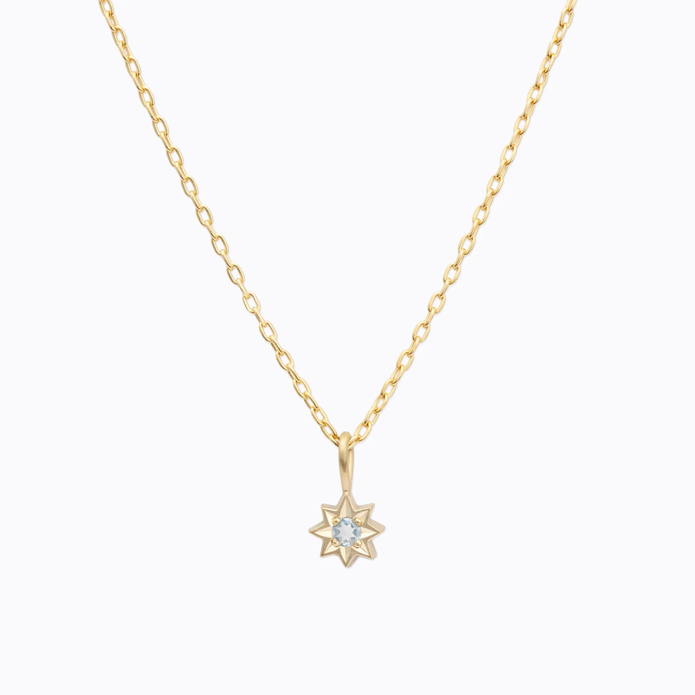 Delicate 14k gold star pendant necklace with light blue gemstone, minimalist white background