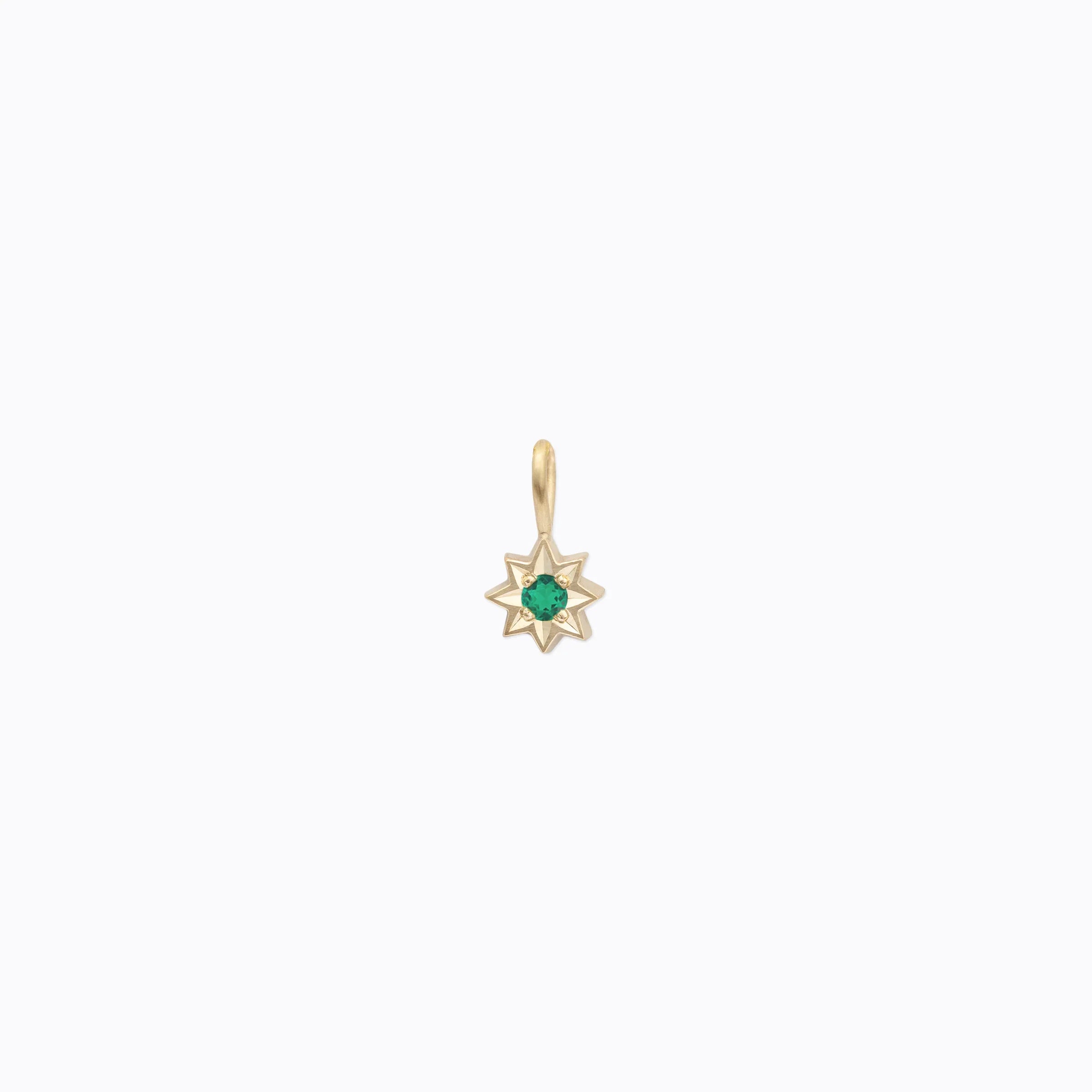Delicate 14k gold star pendant with central green gemstone on soft white background