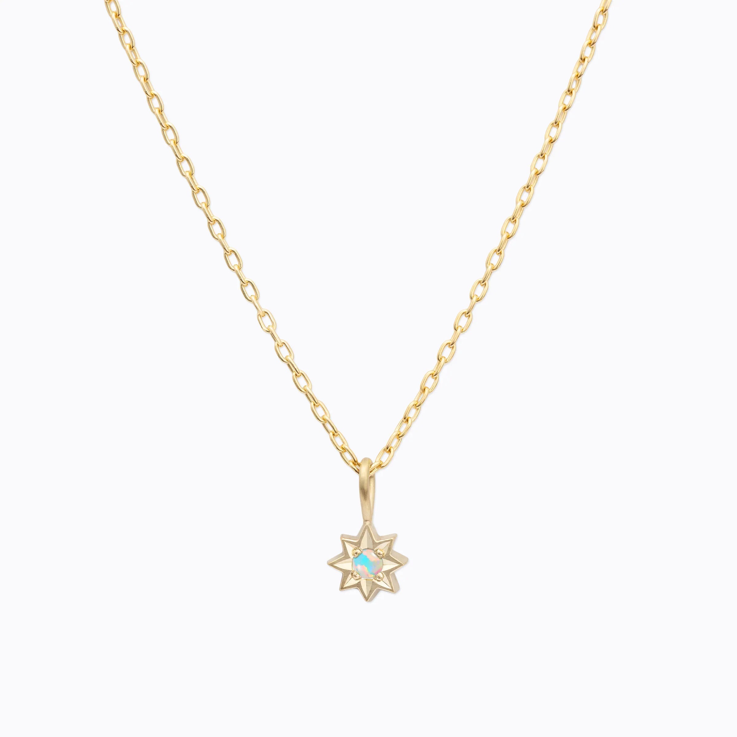 Delicate gold star pendant necklace with opal center on soft light background