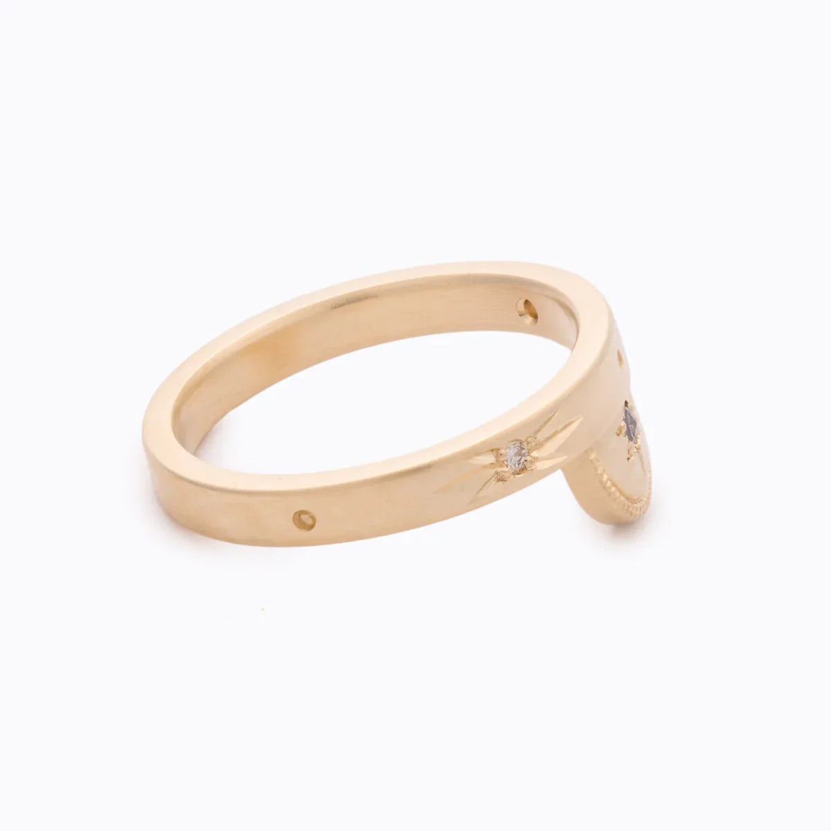 Close-up of handcrafted fairmined gold ring with small diamonds set in star engravings on clean white background