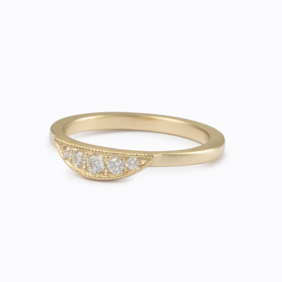 Fairmined gold curved ring with five hand-set diamonds on soft white background