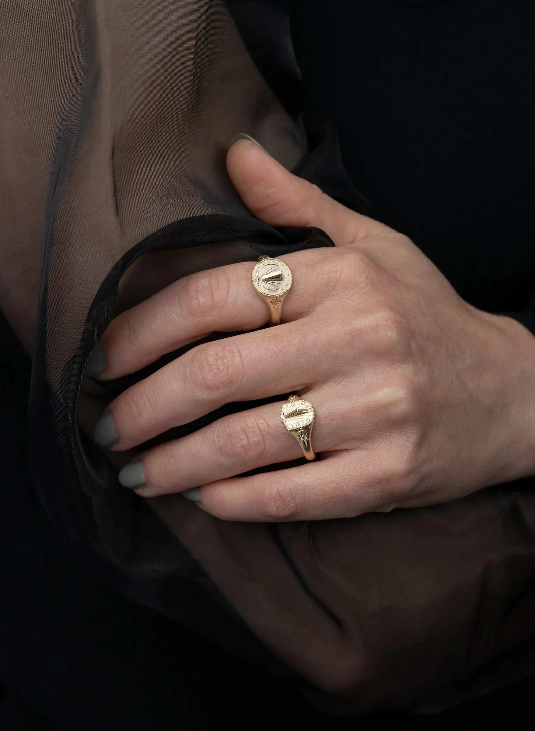 Woman's hand wearing two handcrafted Fairmined gold sundial rings with engraved hour markers, soft natural light