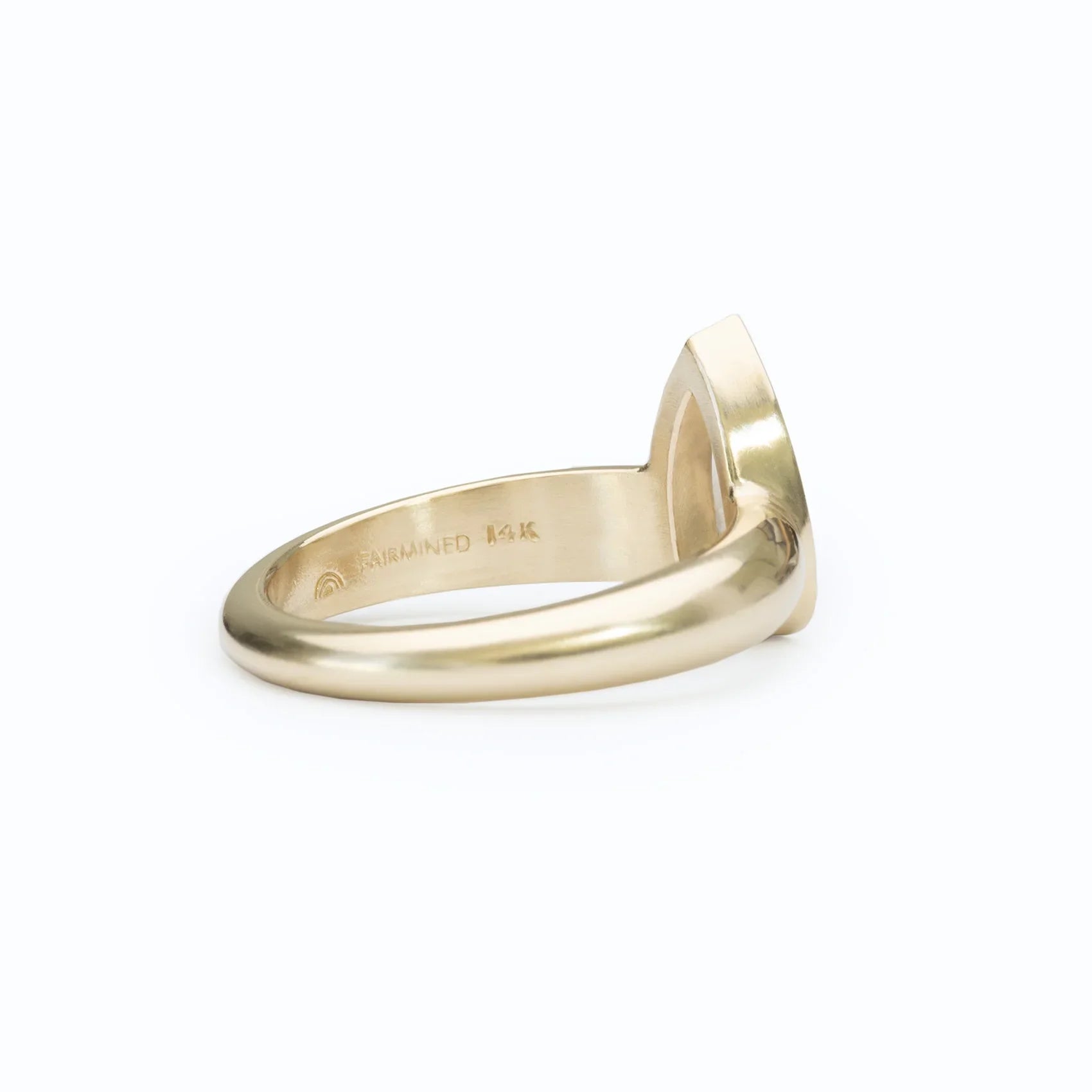 Side view of 14k Fairmined yellow gold ring with smooth band on white background