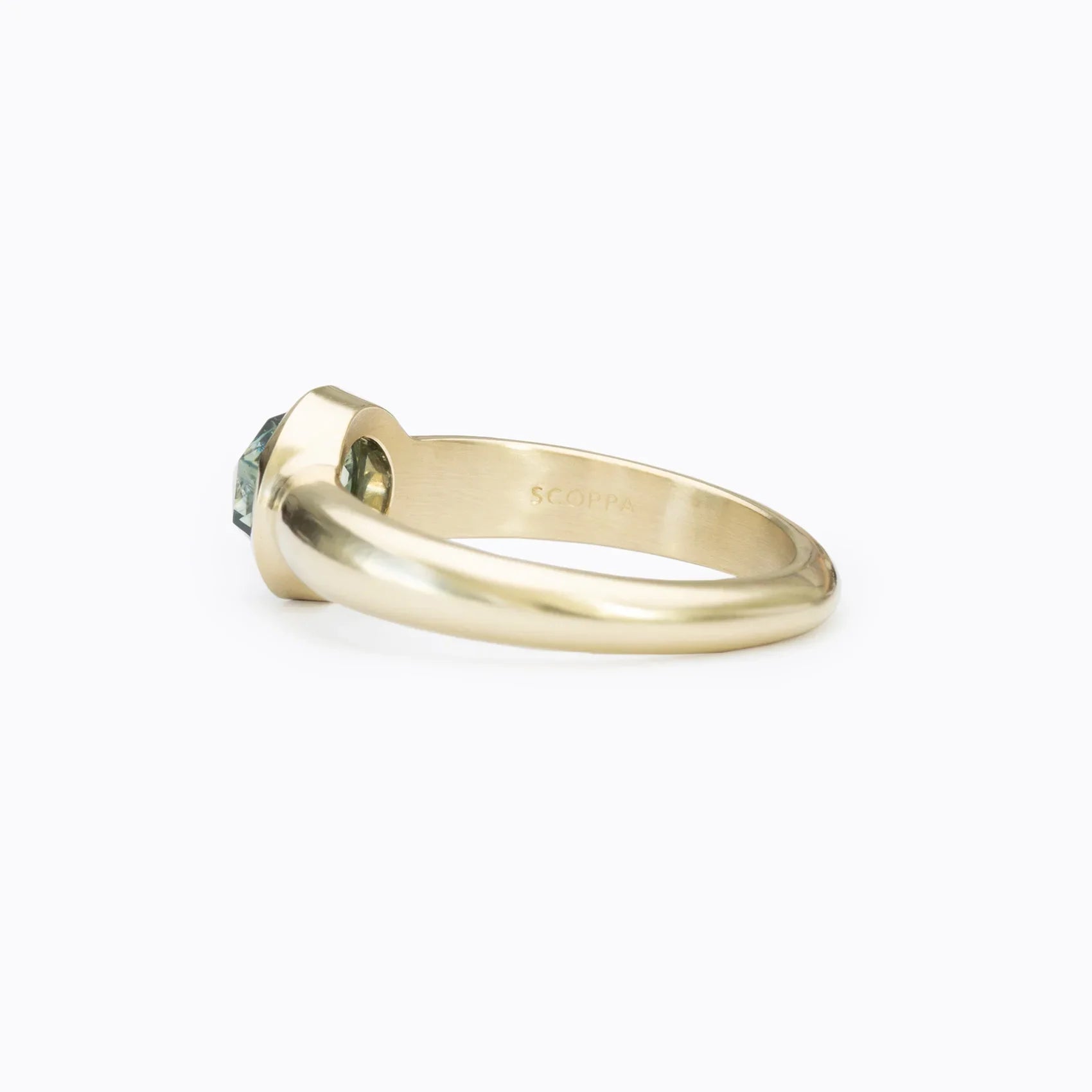 Side view of 14k gold ring with round blue sapphire set in handcrafted elegant band on white background