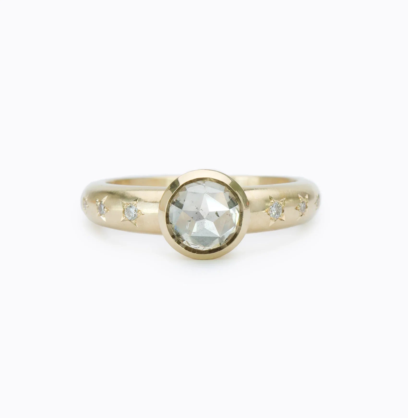 Close-up of gold ring with central rose-cut diamond and small star-set diamonds on band, clean white background