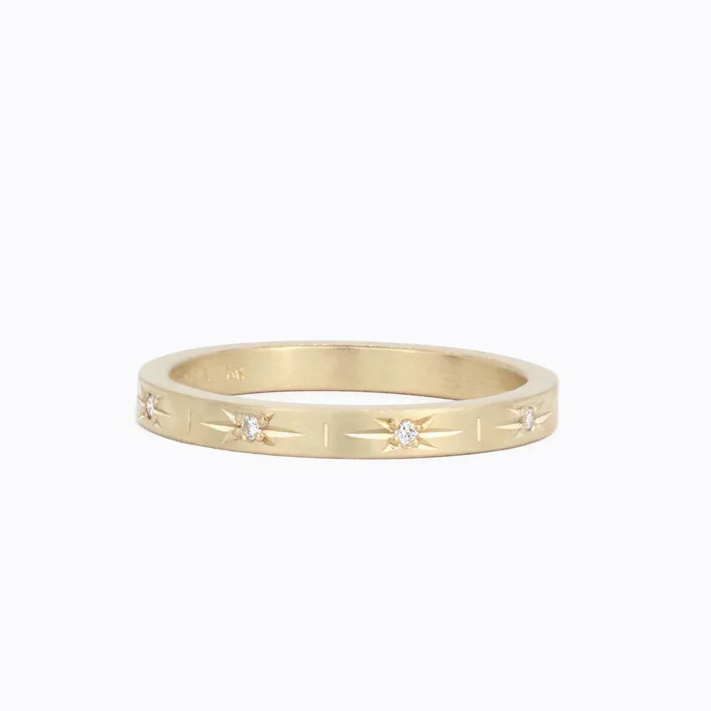 Elegant Fairmined gold ring with hand-engraved star motifs and small diamonds on white background