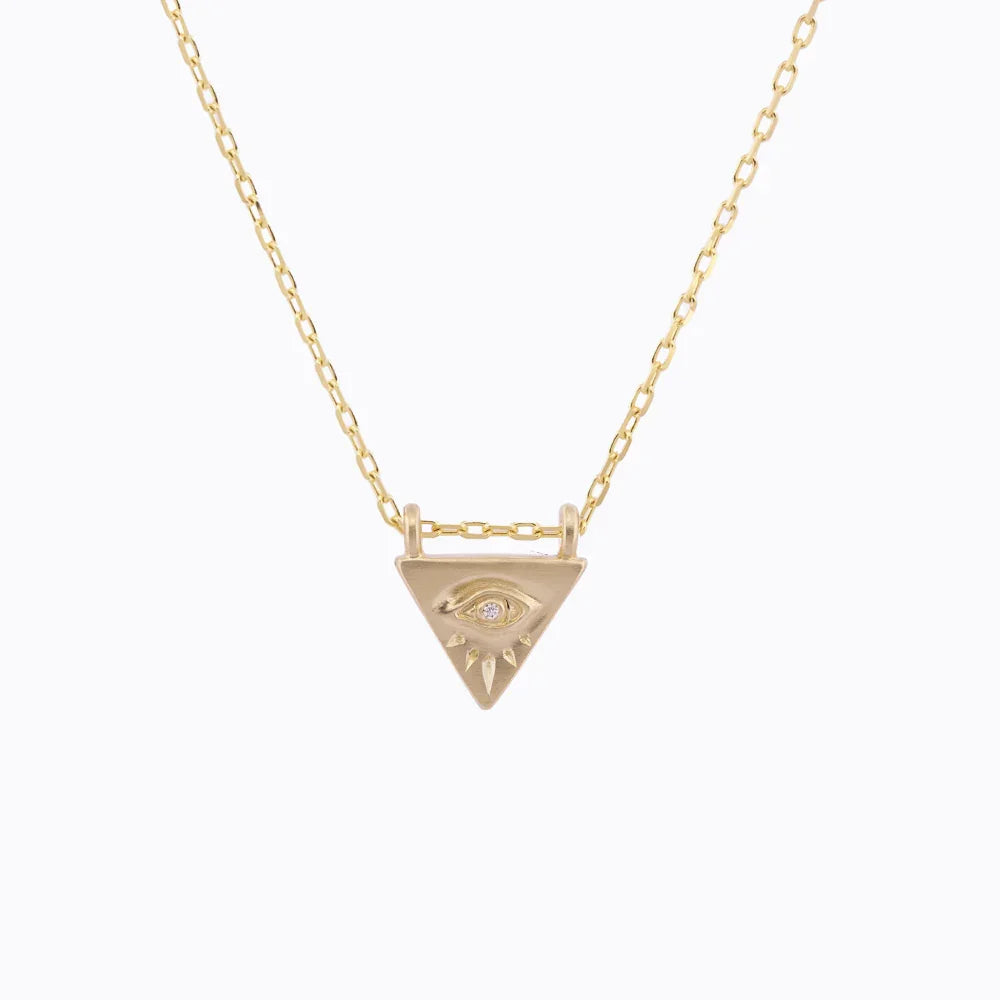 Hand-fabricated gold triangle pendant necklace with engraved eye and diamond detail on soft white background