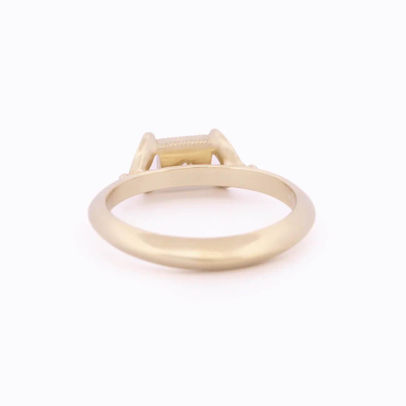 Side view of elegant matte 18k yellow gold ring with rectangular setting on soft white background