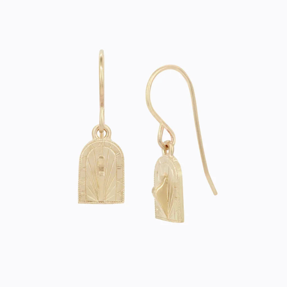 Delicate gold sundial drop earrings with hand-engraved hour markers on soft white background
