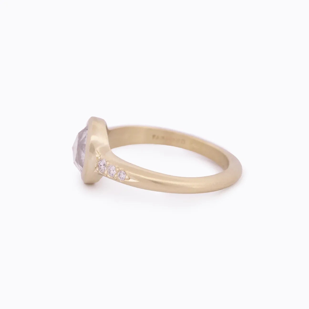 Side view of elegant Fairmined gold ring with bezel-set moonstone and four small diamonds on band