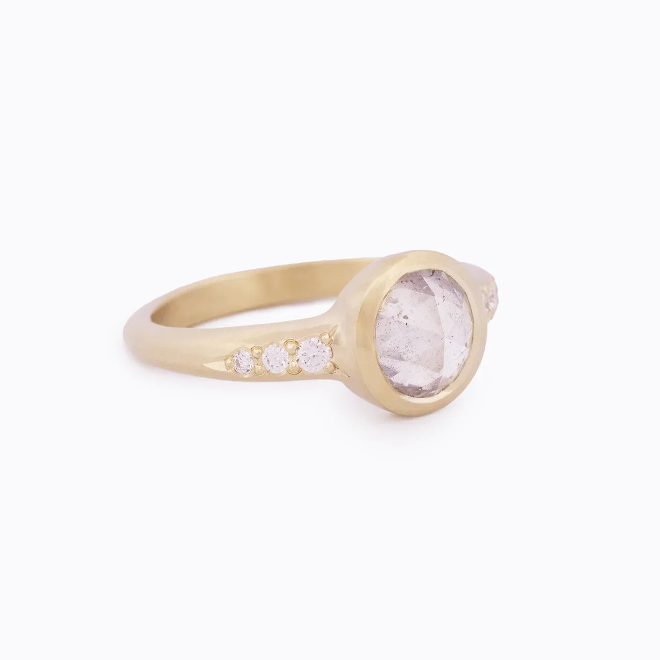 Elegant gold ring with large faceted rose quartz center and four small accent diamonds on soft white background