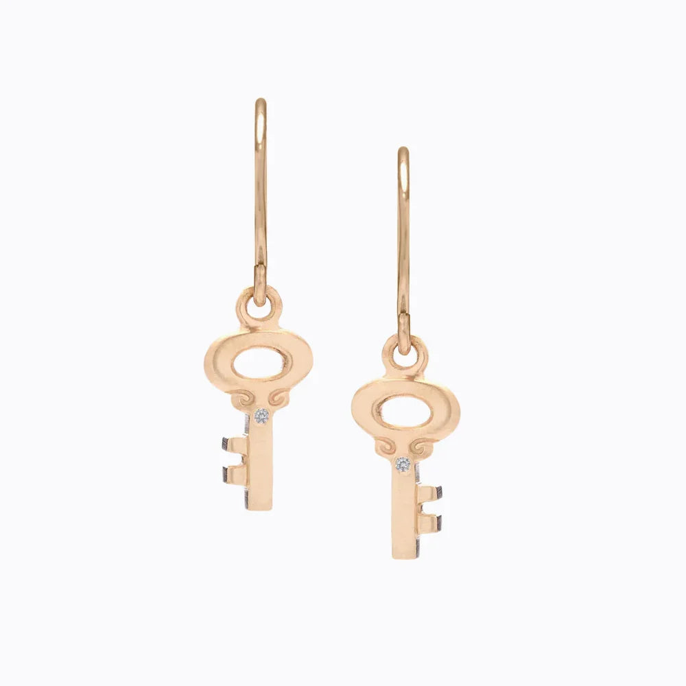 Pair of elegant gold key-shaped drop earrings with small diamond accents on plain white background