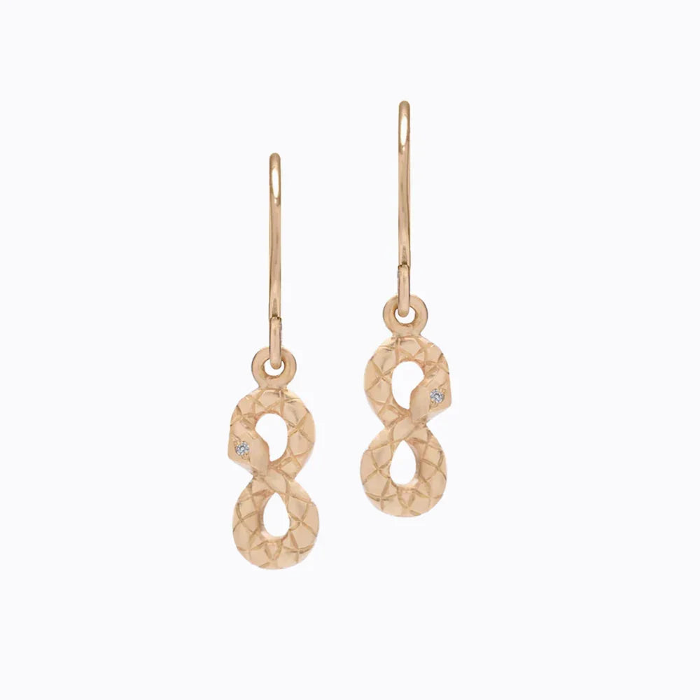 Delicate Fairmined gold snake earrings with hand-engraved scale texture and small diamond accents on white background