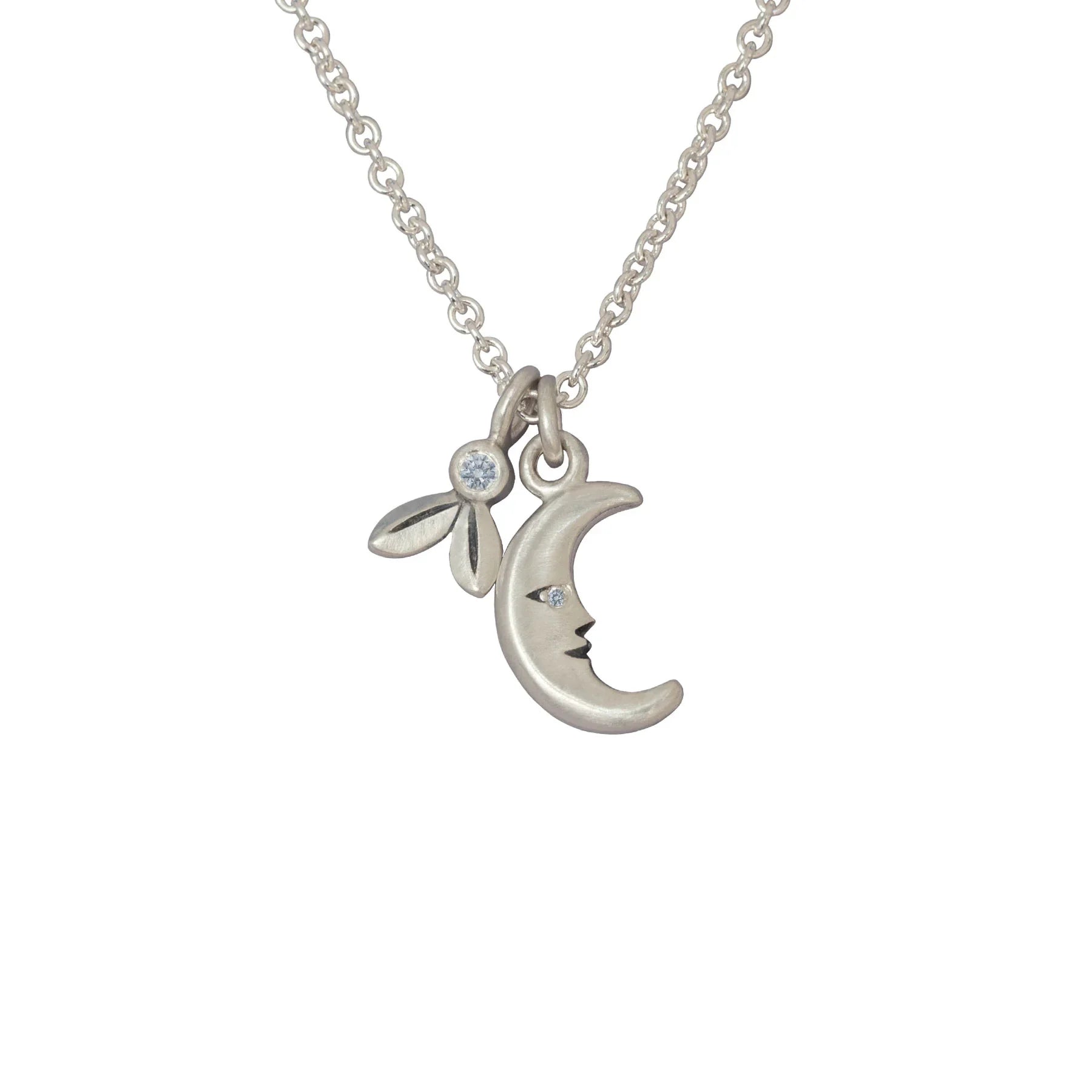 Delicate silver moon and three-leaf charm necklace with small gemstones on white background