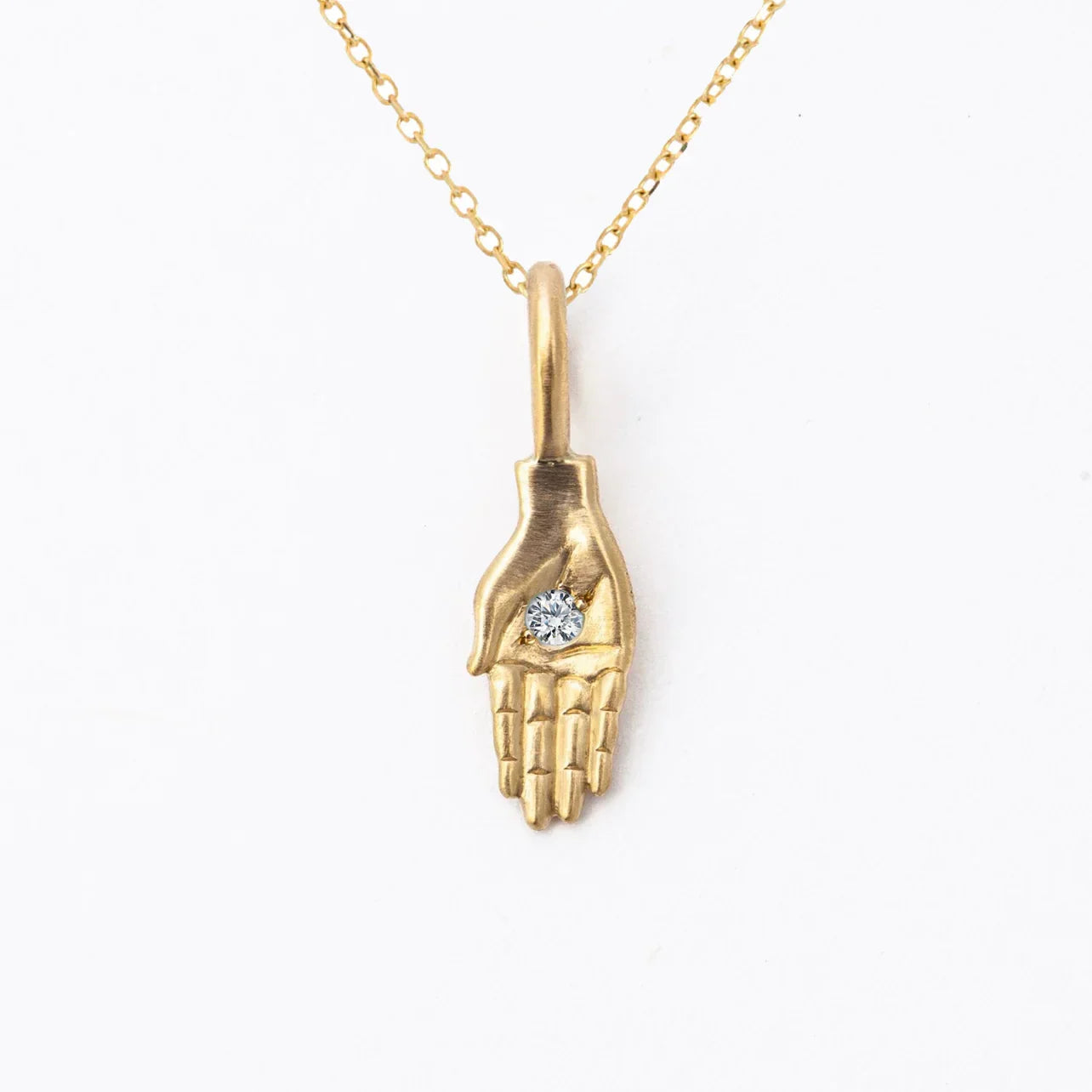 Delicate 18k gold hand pendant necklace with centered sparkling diamond on white background