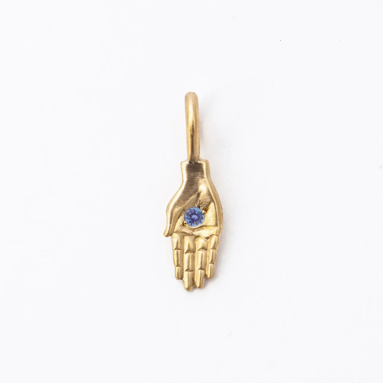 Handcrafted 18k gold hand pendant with blue gemstone, minimalist white background, soft natural light