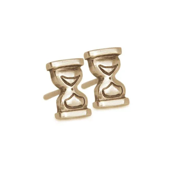 Close-up of handcrafted 14k gold hourglass stud earrings with hand-engraved details on cream background