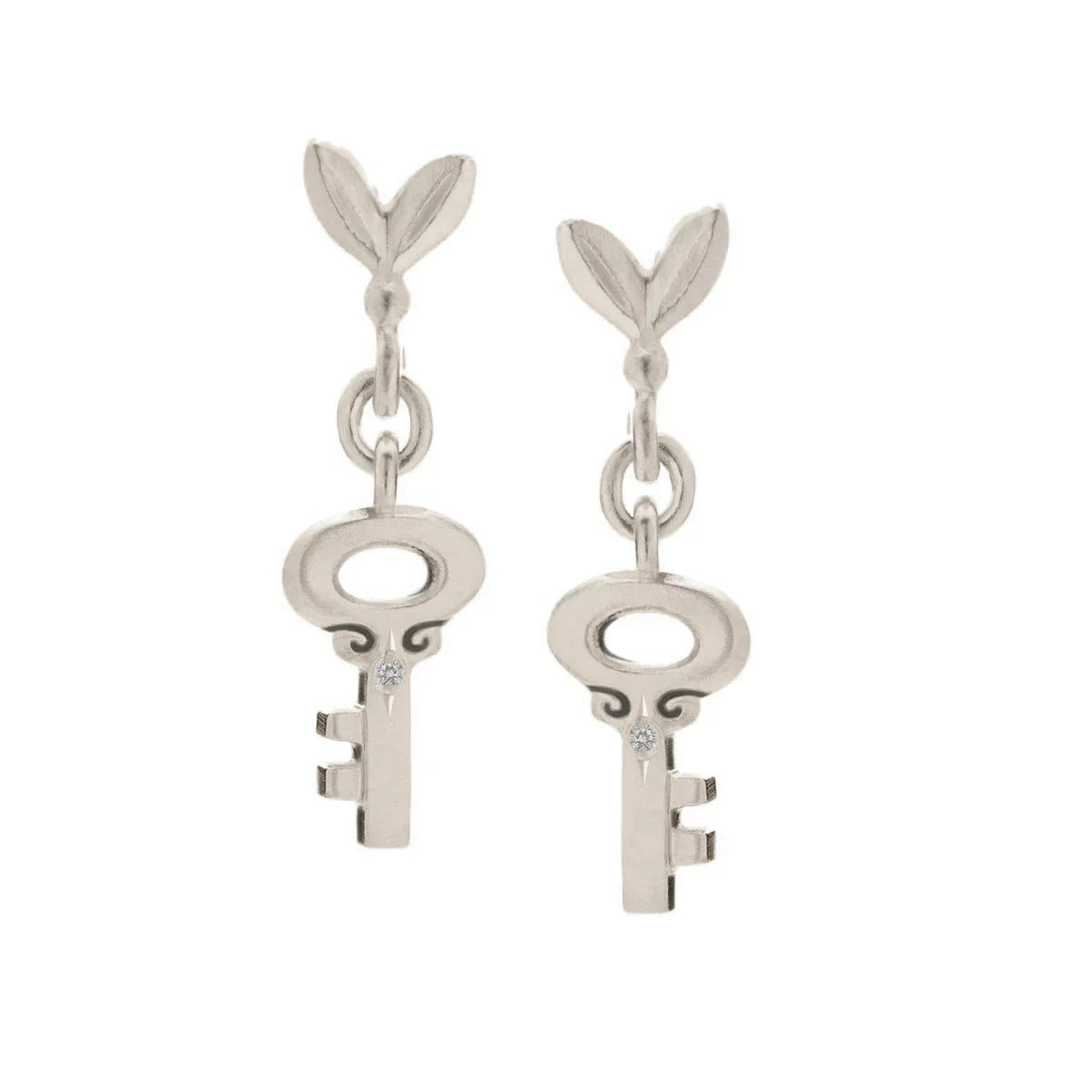 Pair of hand-fabricated silver key earrings with delicate leaf detail and small gemstone accents on white background