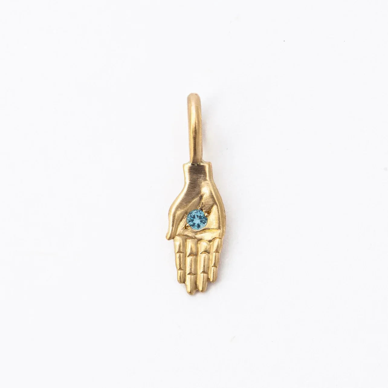 Handcrafted gold palm pendant with blue gemstone center on soft white background