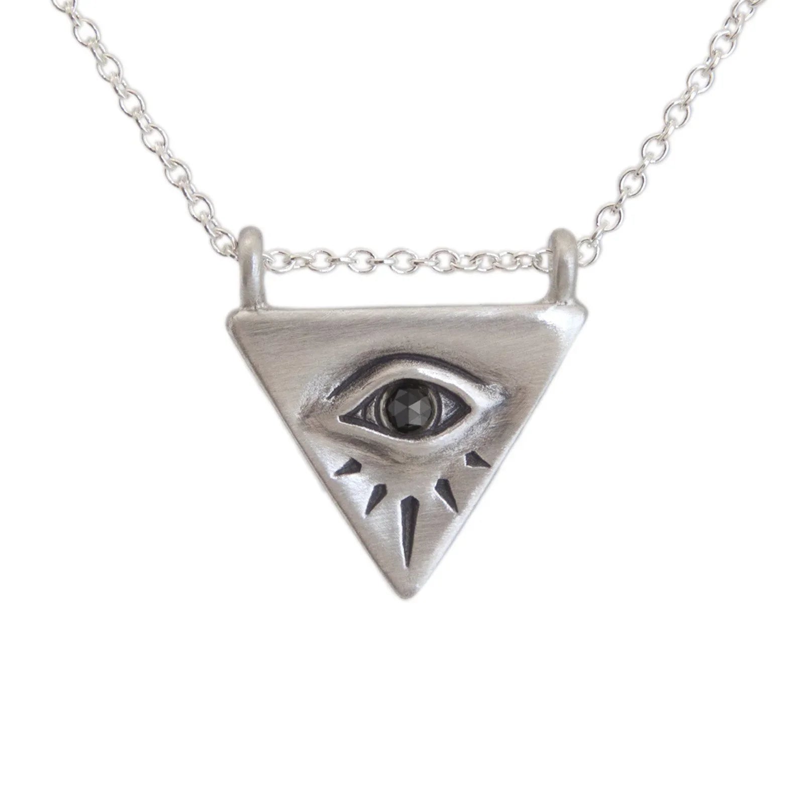 Close-up of silver triangular evil eye pendant with black stone and engraved rays, on chain