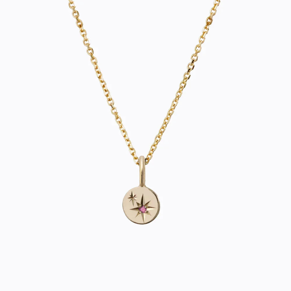 Delicate Fairmined gold pendant necklace with engraved stars and pink tourmaline set, minimalist white background