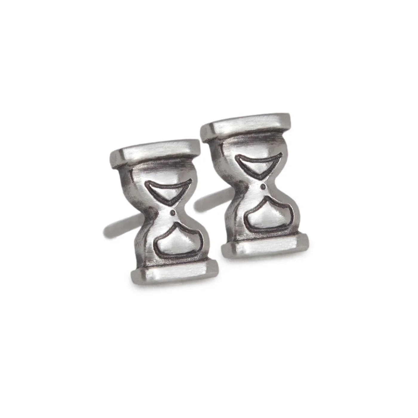 Close-up of handcrafted silver hourglass stud earrings on white background with soft shadows